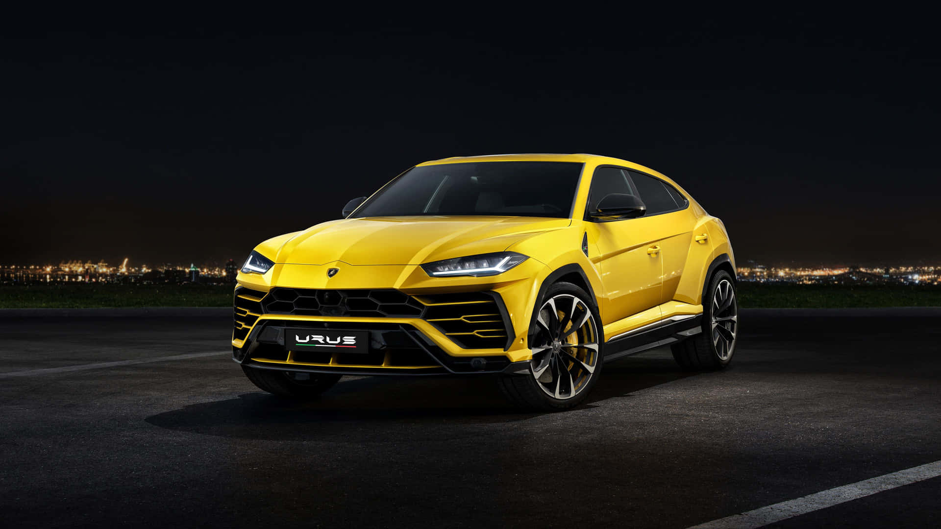 黃色林寶堅尼 Urus SUV 夜間停泊，背景有城市燈光。