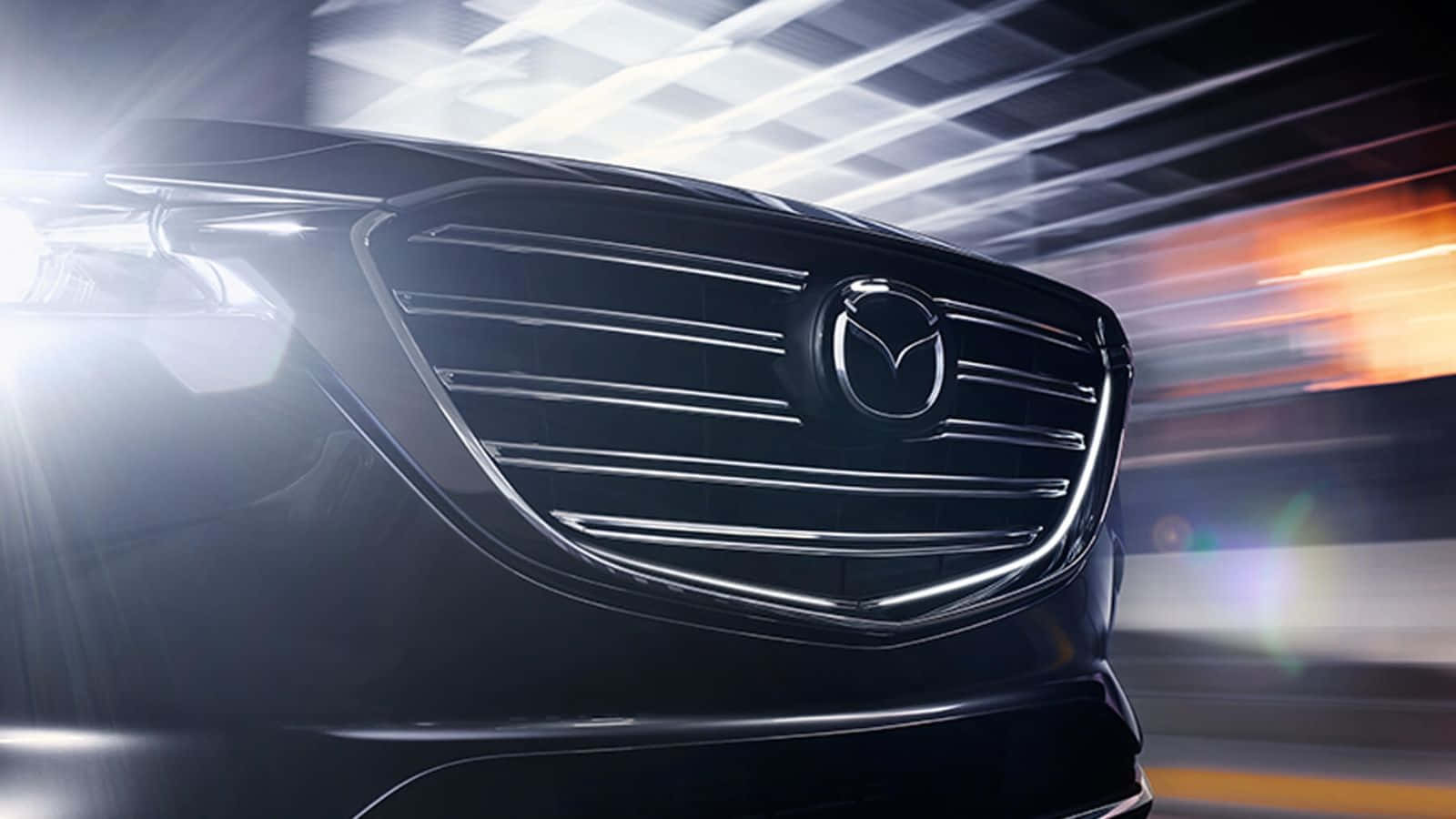 Mazda Cx-9 桌布 壁紙 — 時尚黑色Mazda汽車格柵在明亮燈光下閃耀，背景帶有動態模糊條紋。