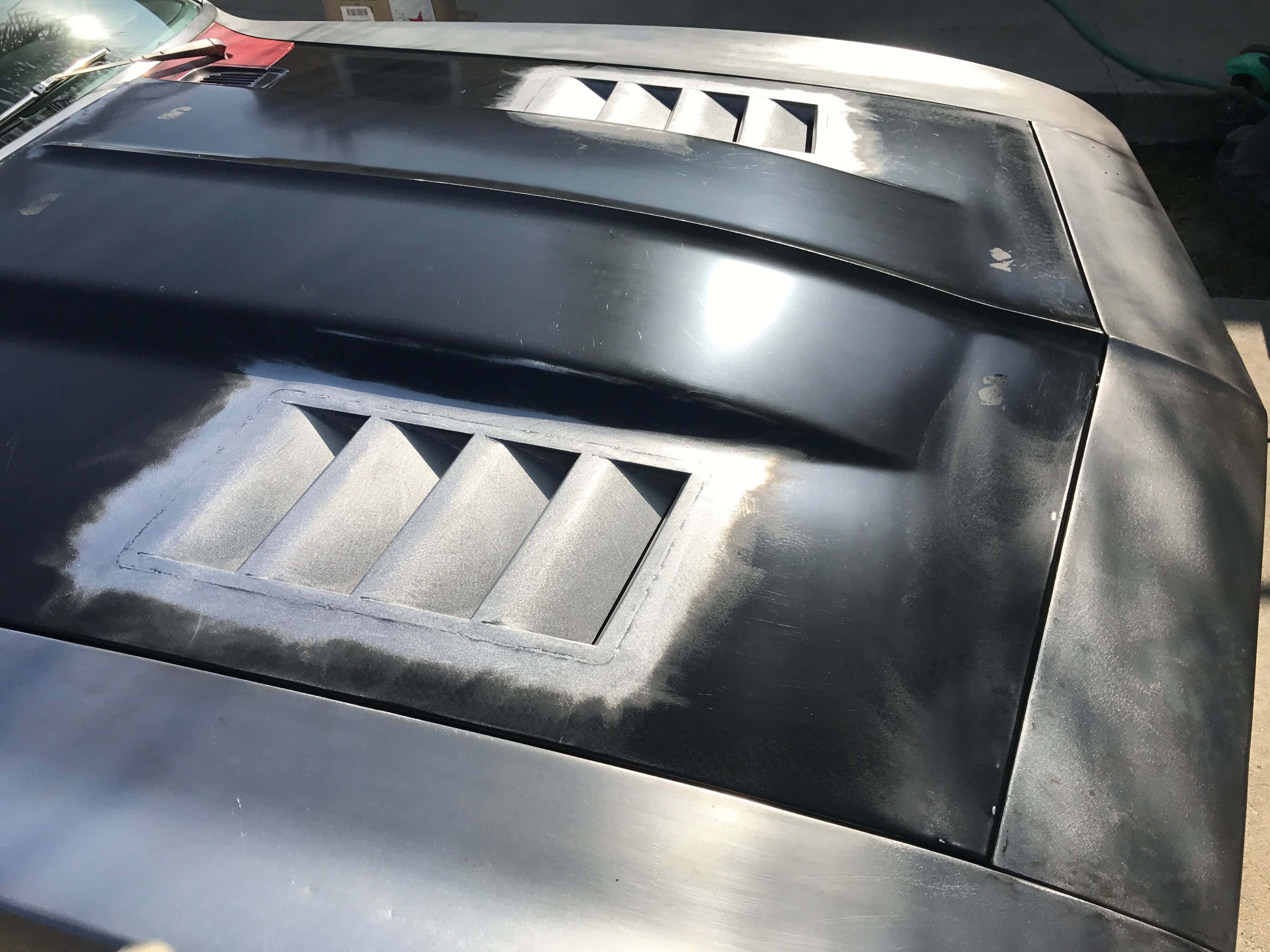 Car Hood 桌布 壁紙 — 時尚黑色汽車引擎蓋的特寫，帶有銀色通風口，反射出明亮的陽光。
