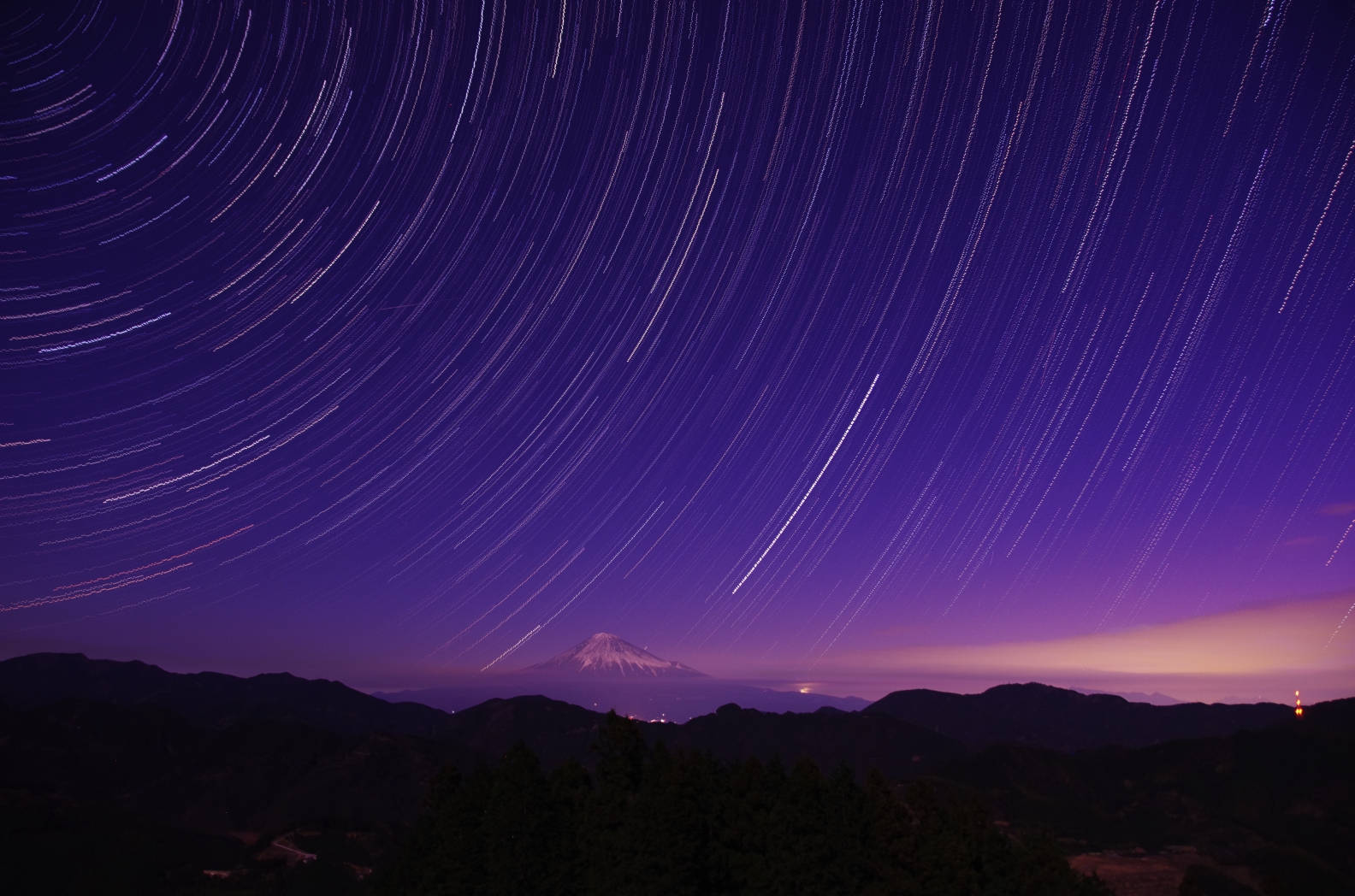 時間延遲攝影媒介 壁紙 — 星軌在夜晚的深紫色天空中，越過白雪覆蓋的富士山頂，劃出弧線。