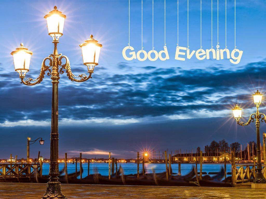 晚安街燈 壁紙 — 復古路燈在暮色天空中溫暖地發光，而「Good Evening」懸掛在寧靜的海濱場景上方。
