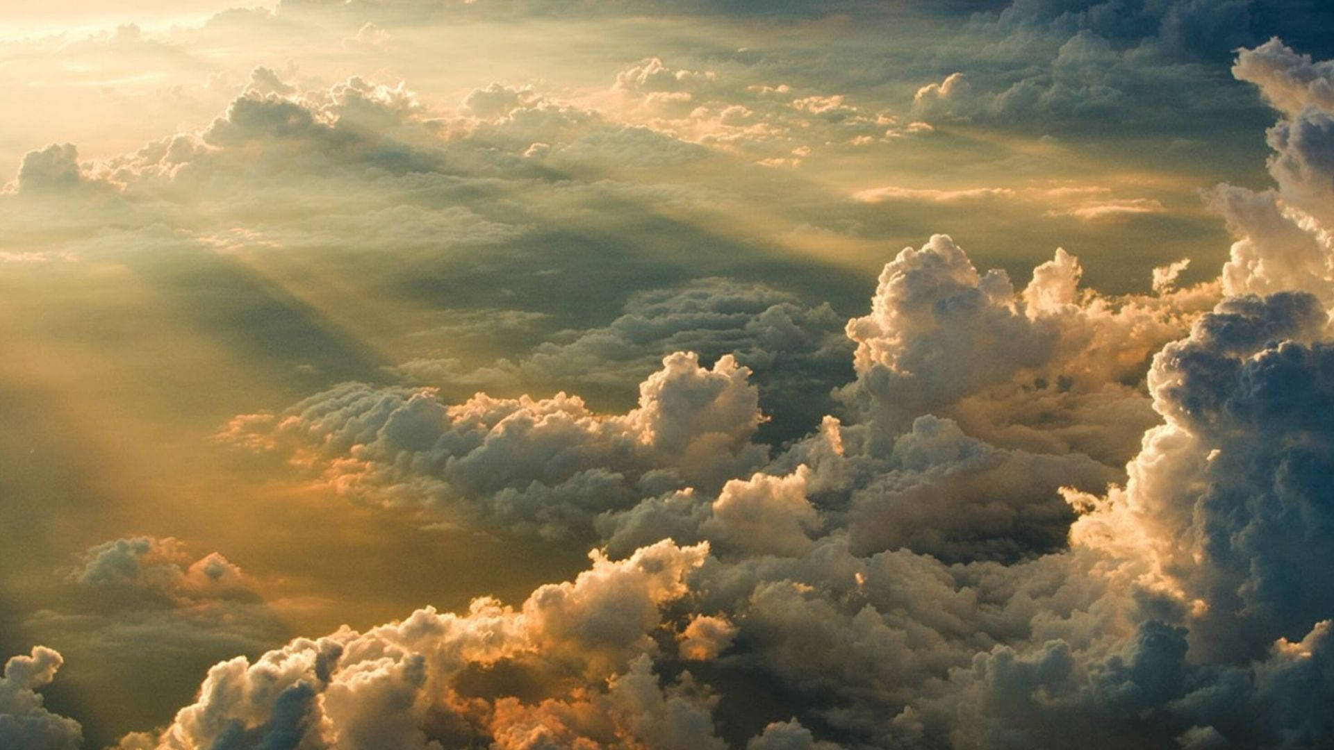 晨光天際 壁紙 — 金色陽光穿透高聳的雲層，在廣闊的天空中投射出溫暖的光芒。