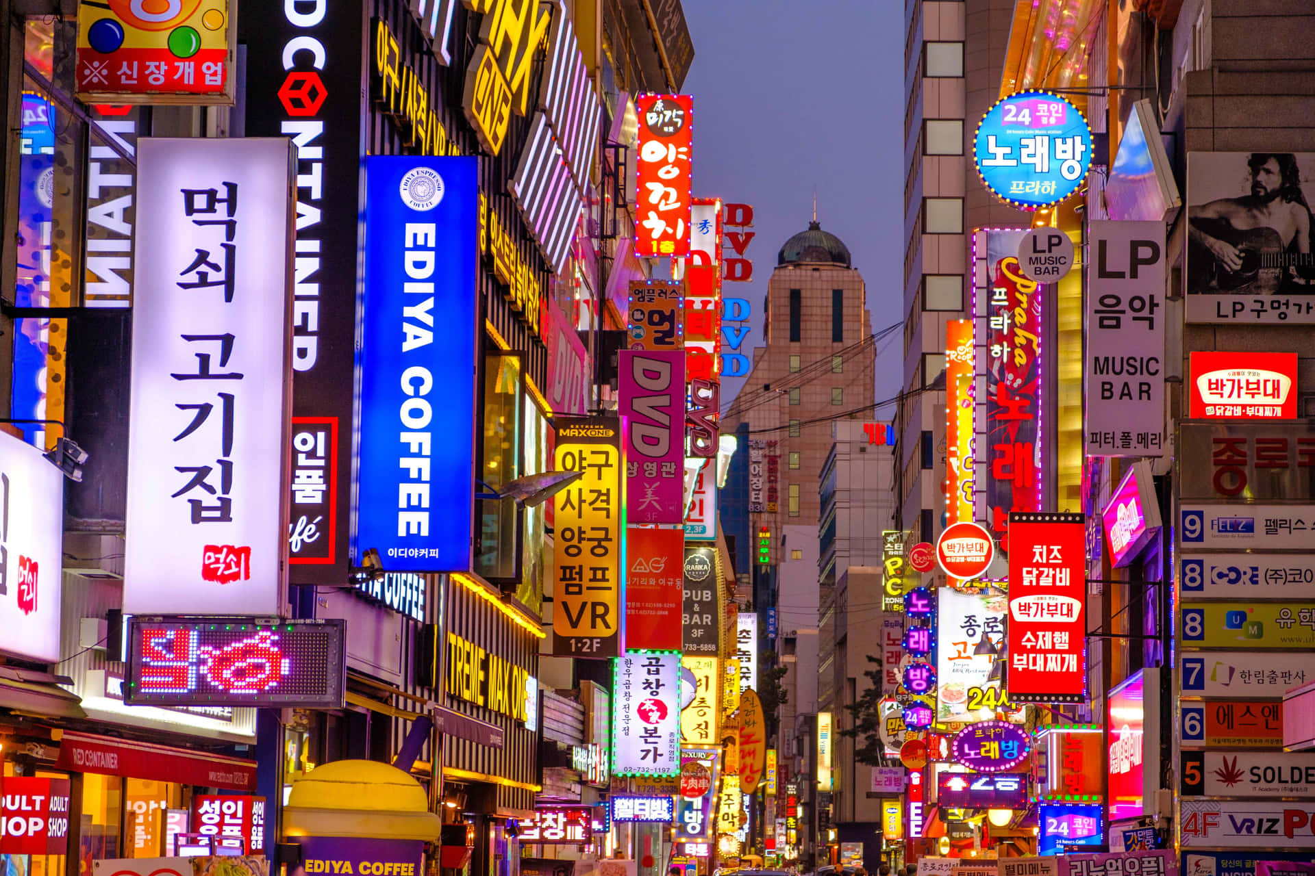 晨曦之國——韓國的美麗風景 壁紙 — 黃昏時分，一條耀眼的城市小巷，佈滿高聳的韓文霓虹招牌，宣傳著充滿活力的夜生活和繁華的商業。