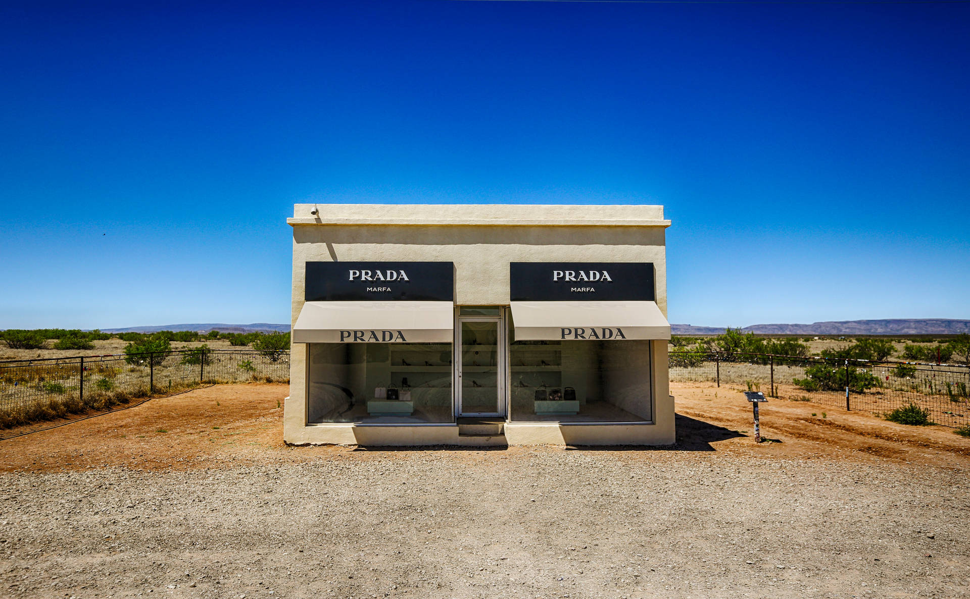 在清澈藍天下，沙漠景觀中的 Prada Marfa 藝術裝置。