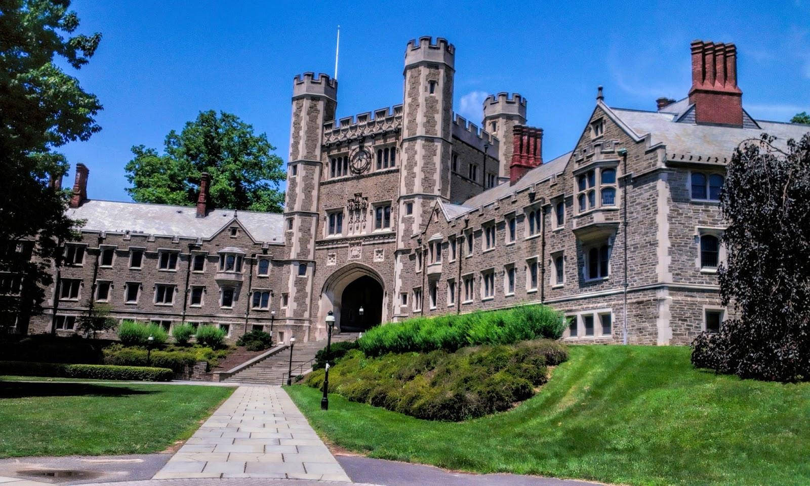 普林斯頓大學美麗的布萊爾大樓 壁紙 — 一座宏偉的石造城堡風格大學建築，設有塔樓和拱形入口，矗立在晴朗的藍天下，兩旁是茂密的綠色草坪和成熟的樹木。