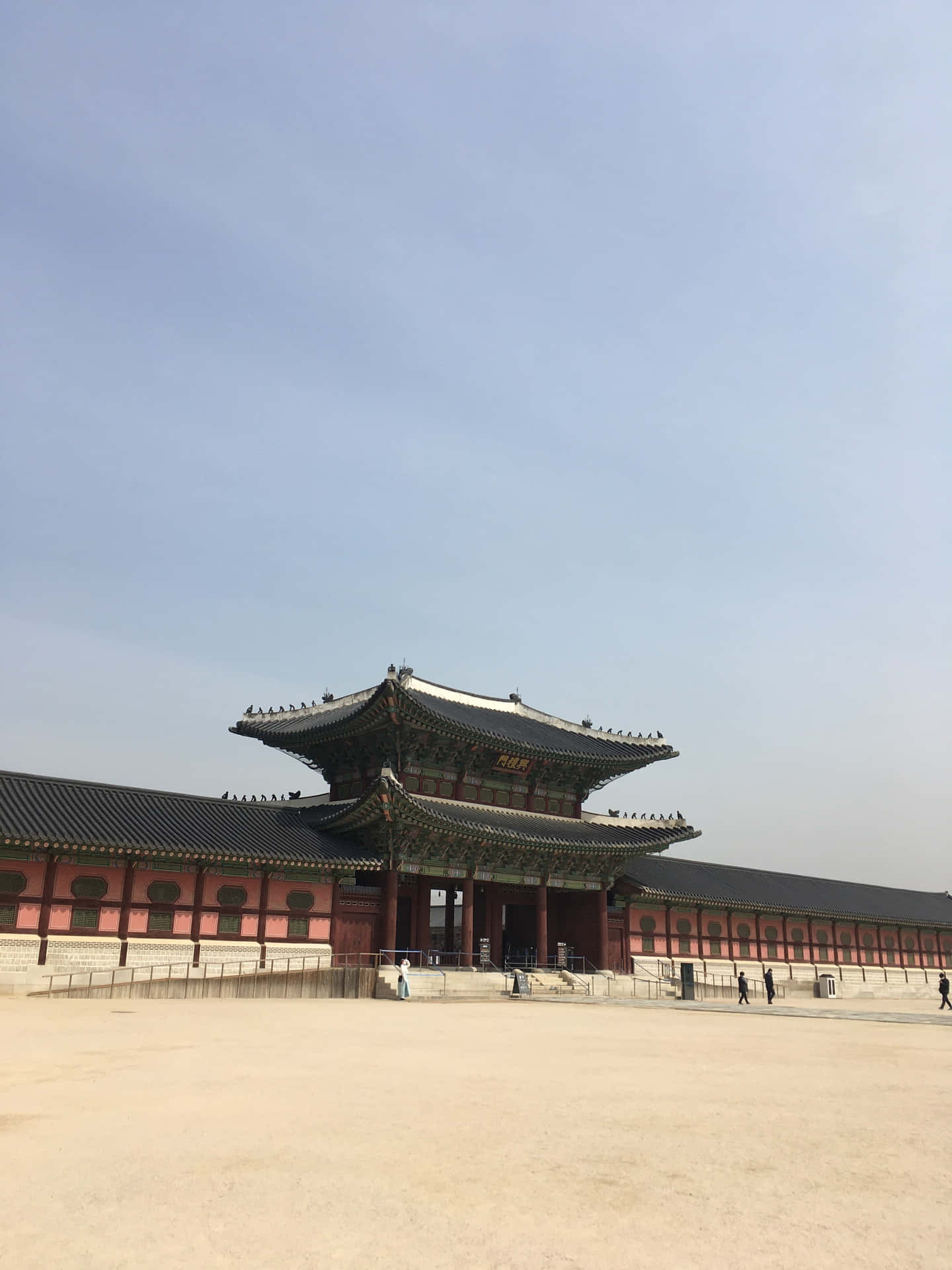 藍天下傳統韓國宮殿，紅牆和彎曲屋頂。