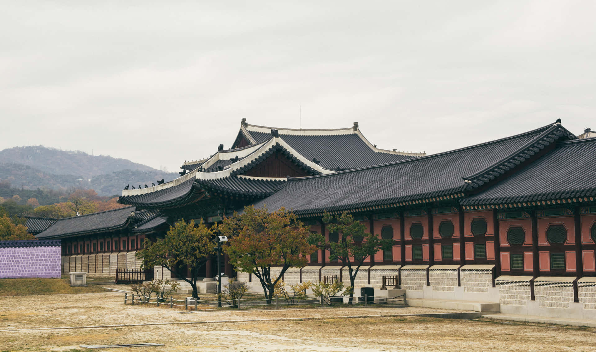 傳統韓國宮殿建築，彎曲屋頂和紅色牆壁，在多雲的天空下。