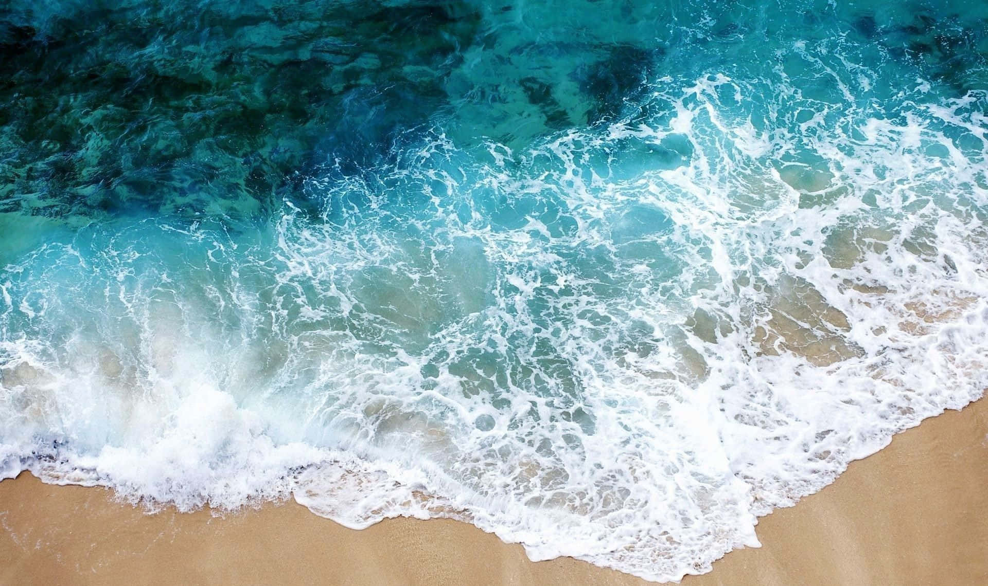 晴日海景 壁紙 — 鳥瞰圖：綠松石色的海浪拍打金色沙灘，泛起白色泡沫。