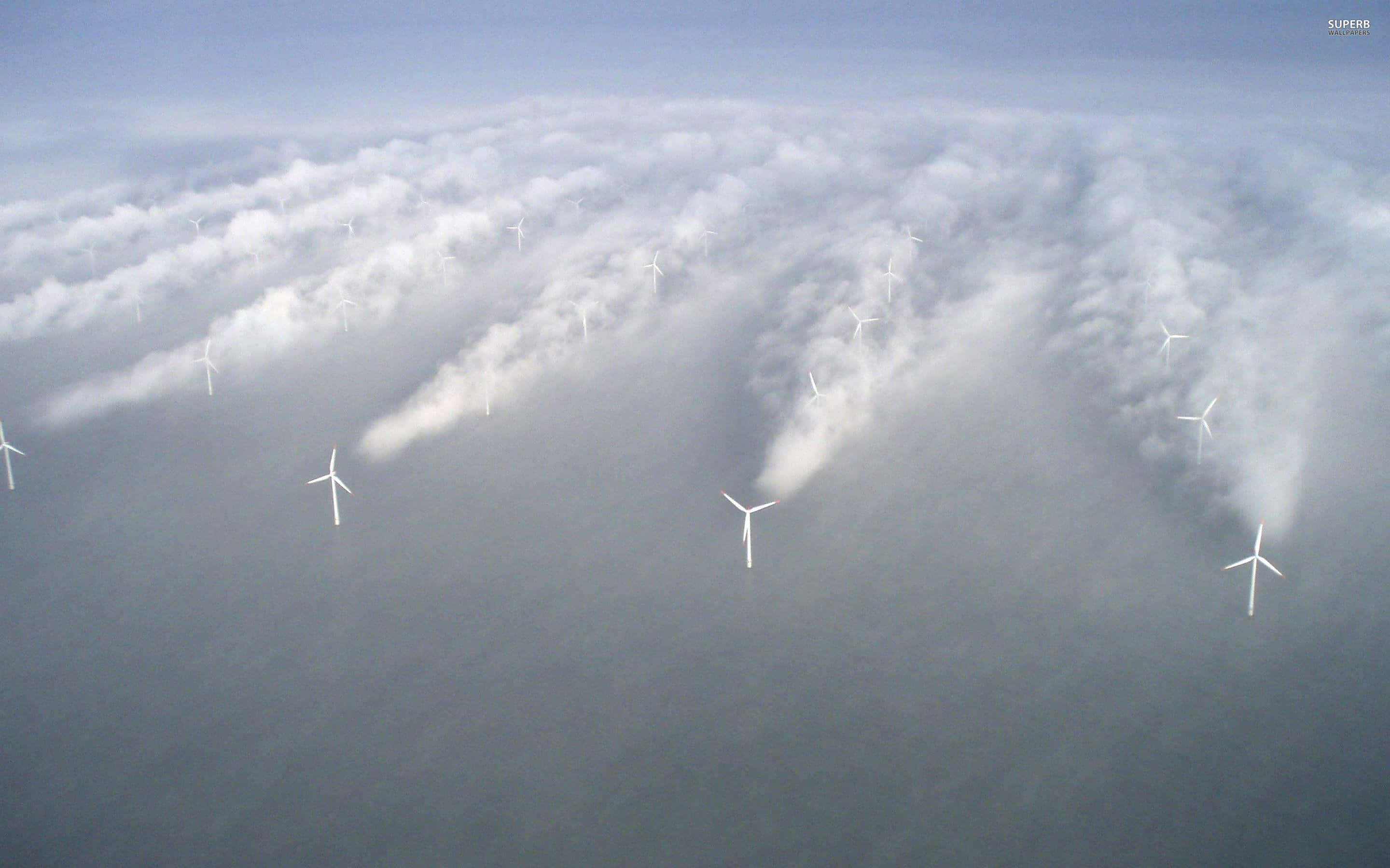 Wind 桌布 壁紙 — 晴朗天空下，風力渦輪機穿過雲層，俯瞰廣闊海洋的航拍視圖。
