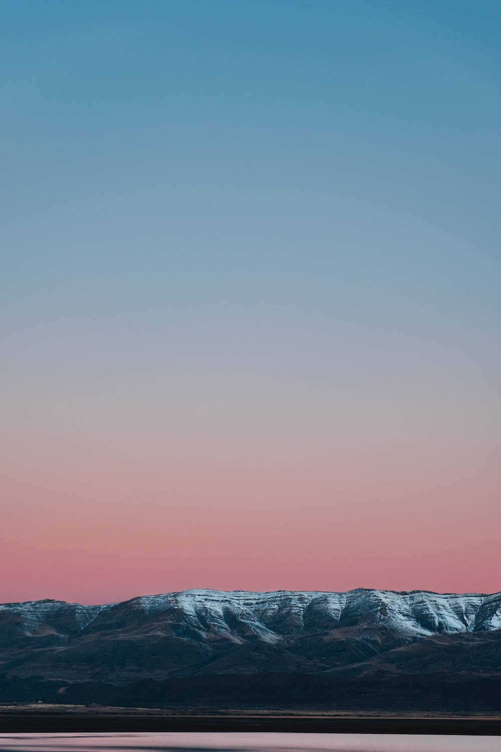 黃昏時分白雪覆蓋的山脈，天空呈現藍色和粉色