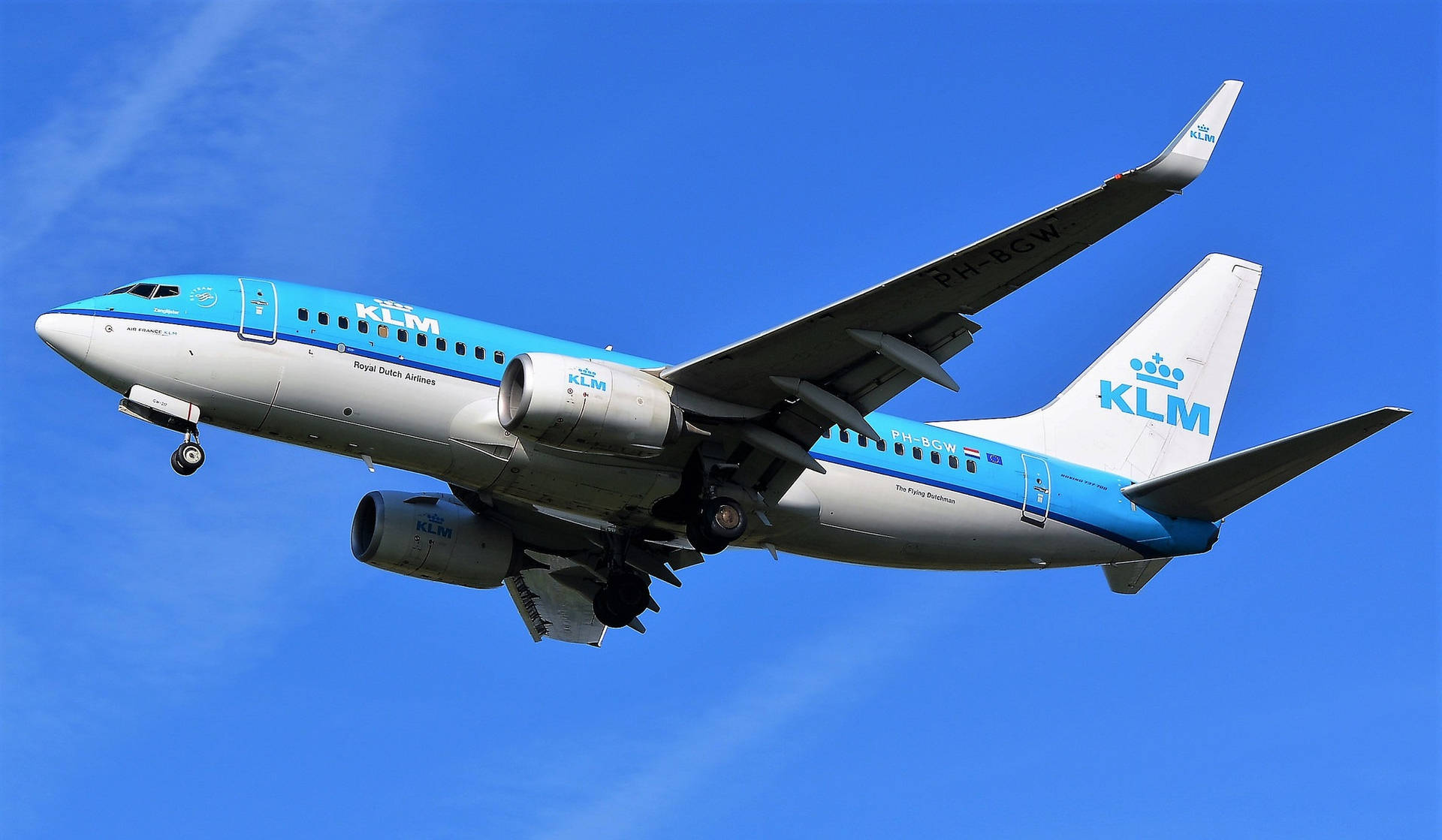 荷蘭皇家航空飛機在藍天中飛行，起落架放下
