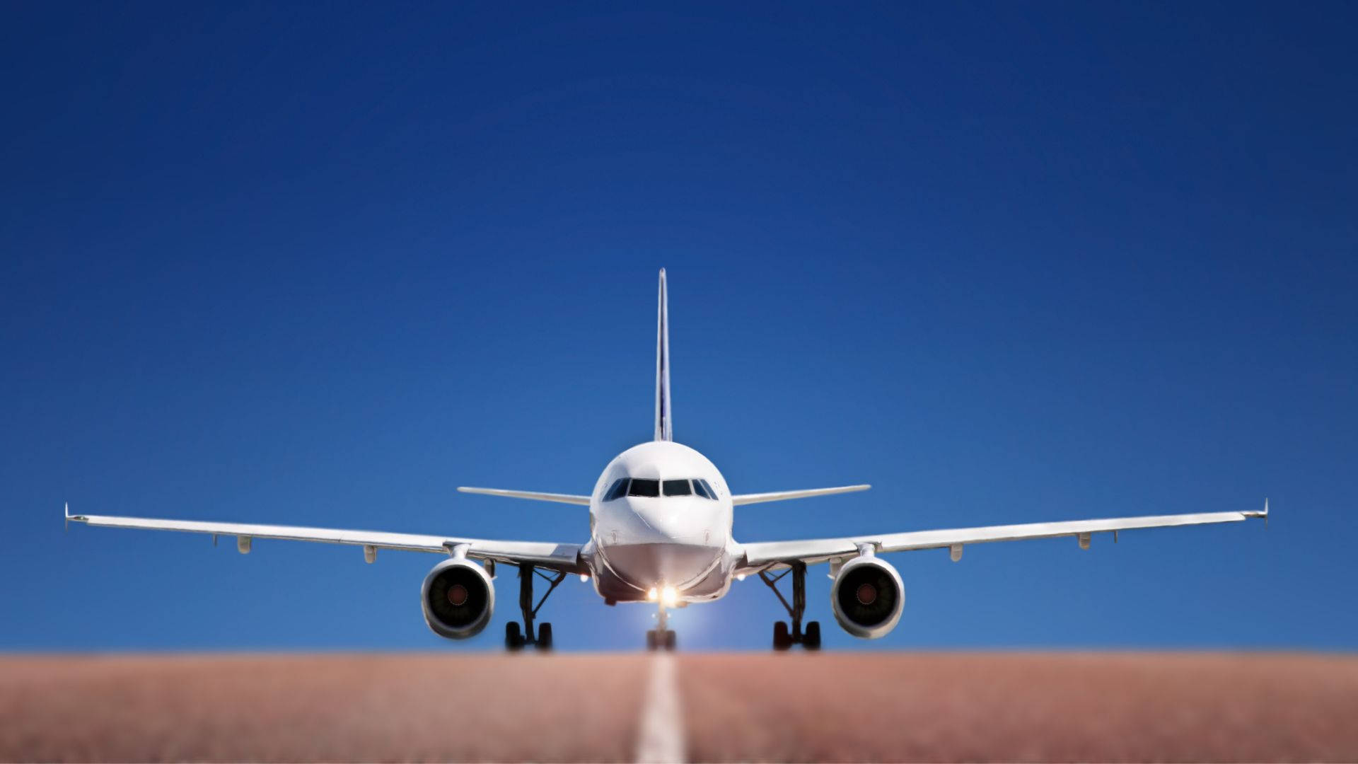 晴空下的飛機跑道 壁紙 — 一架白色客機在晴朗的藍天下接近跑道，降落燈閃爍著光芒。