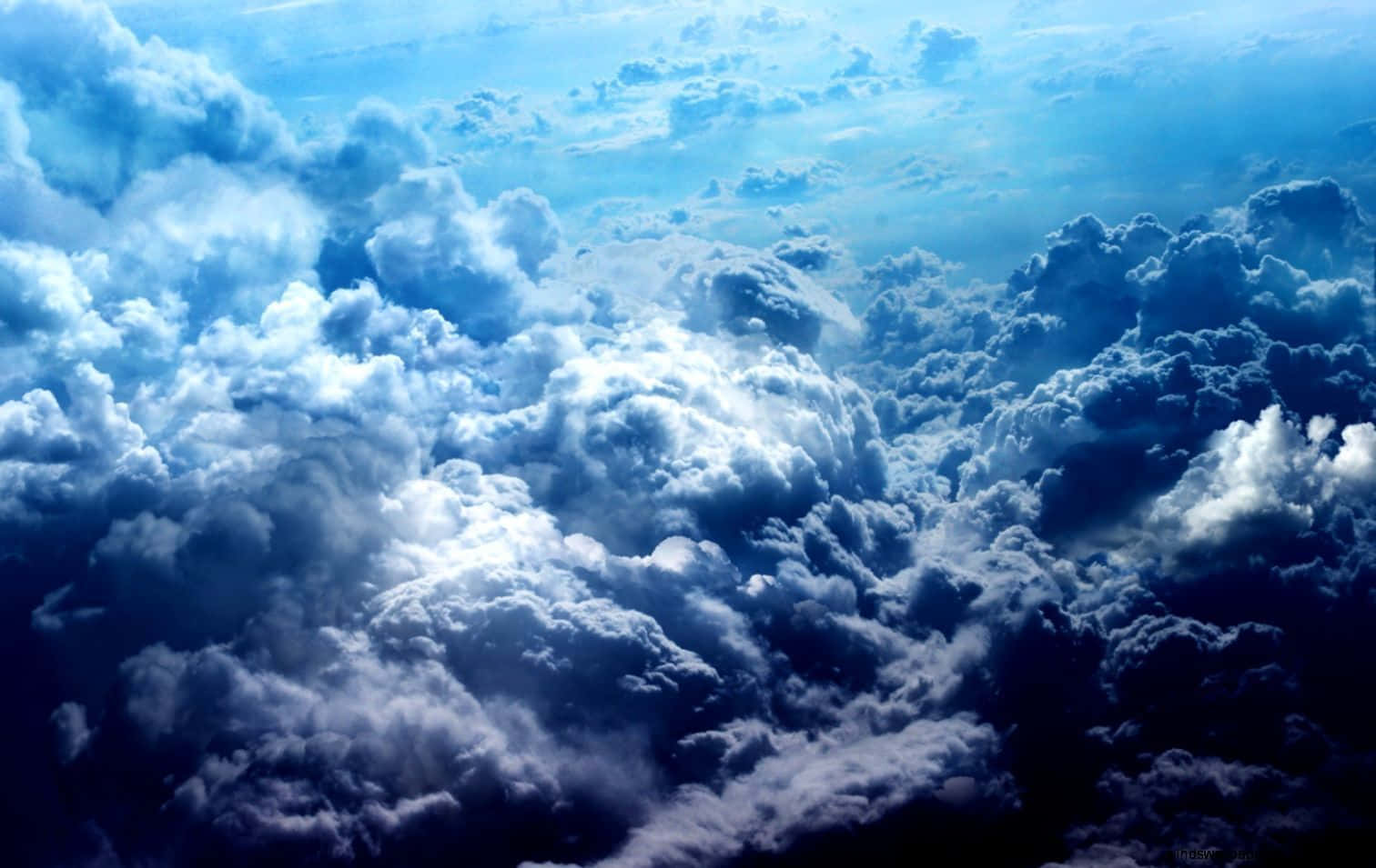 晴空萬里，鮮豔藍雲 壁紙 — 從上方觀看，大片蓬鬆的雲朵在明亮的藍天上延伸，陽光穿透其中。