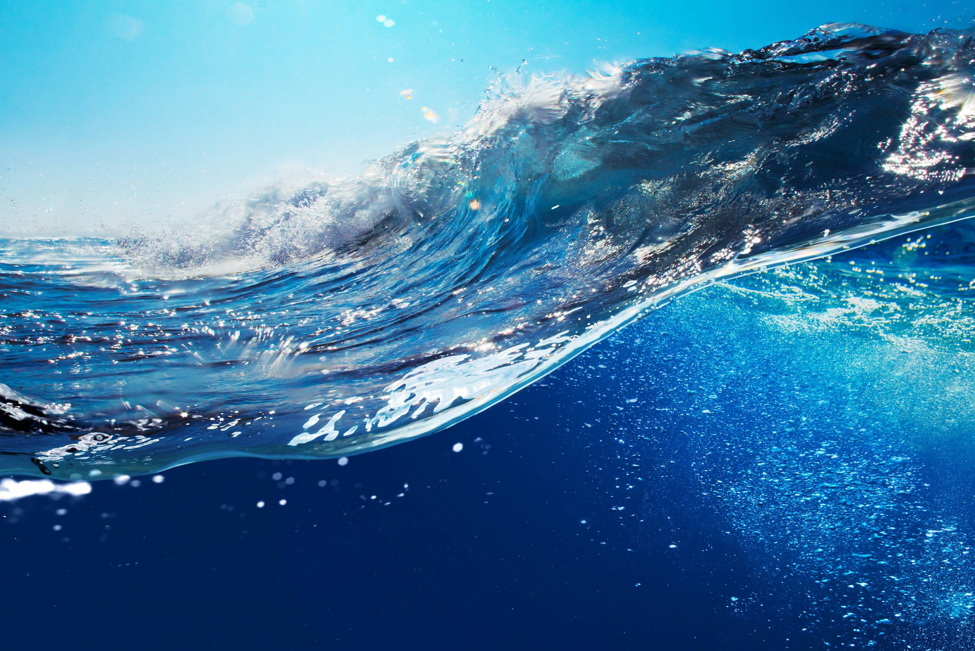 一道強勁的海浪在陽光和水下氣泡中破碎。