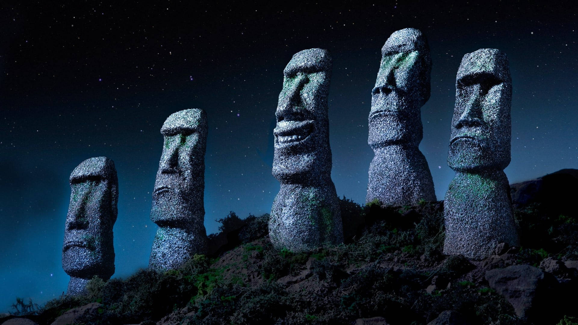 智利石雕人頭像 壁紙 — 五座古老的石像摩艾雕像在星空夜空下，在岩石山丘上莊嚴地矗立，周圍散發著藍色光芒。