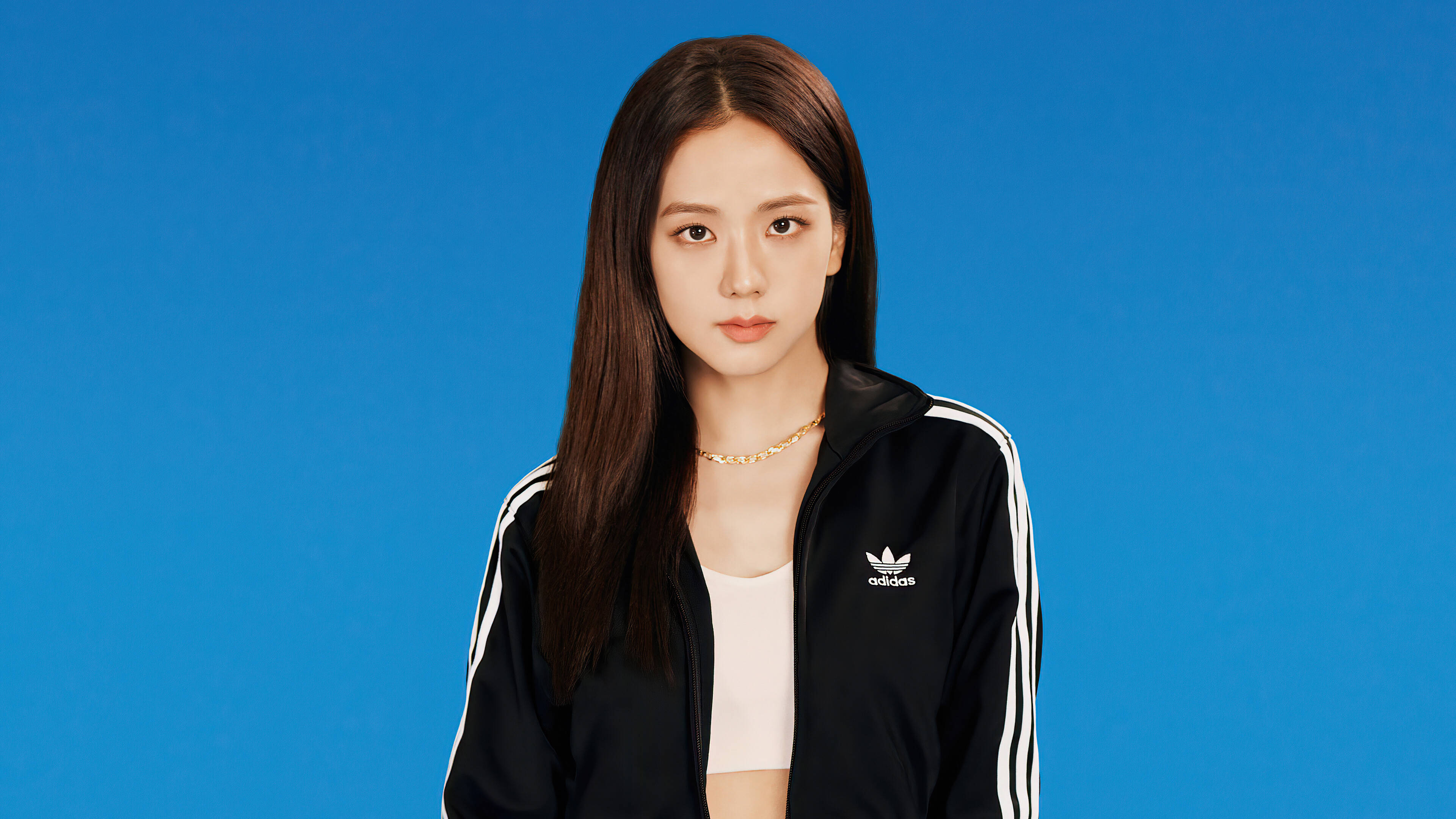 智秀 Adidas 2020 造型 壁紙 — 一位長黑髮的年輕女性穿著黑色Adidas運動外套，背景為純藍色。