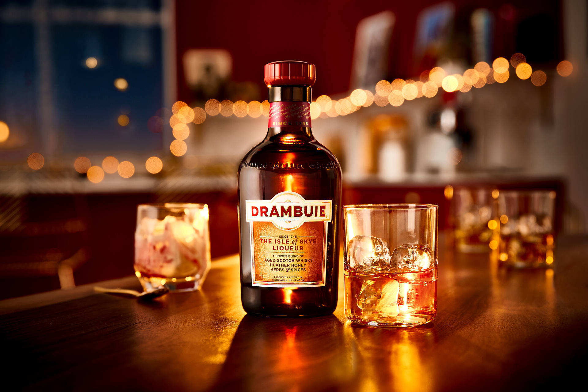 夜晚吧檯上 Drambuie 利口酒瓶和加冰的酒杯，搭配串燈。