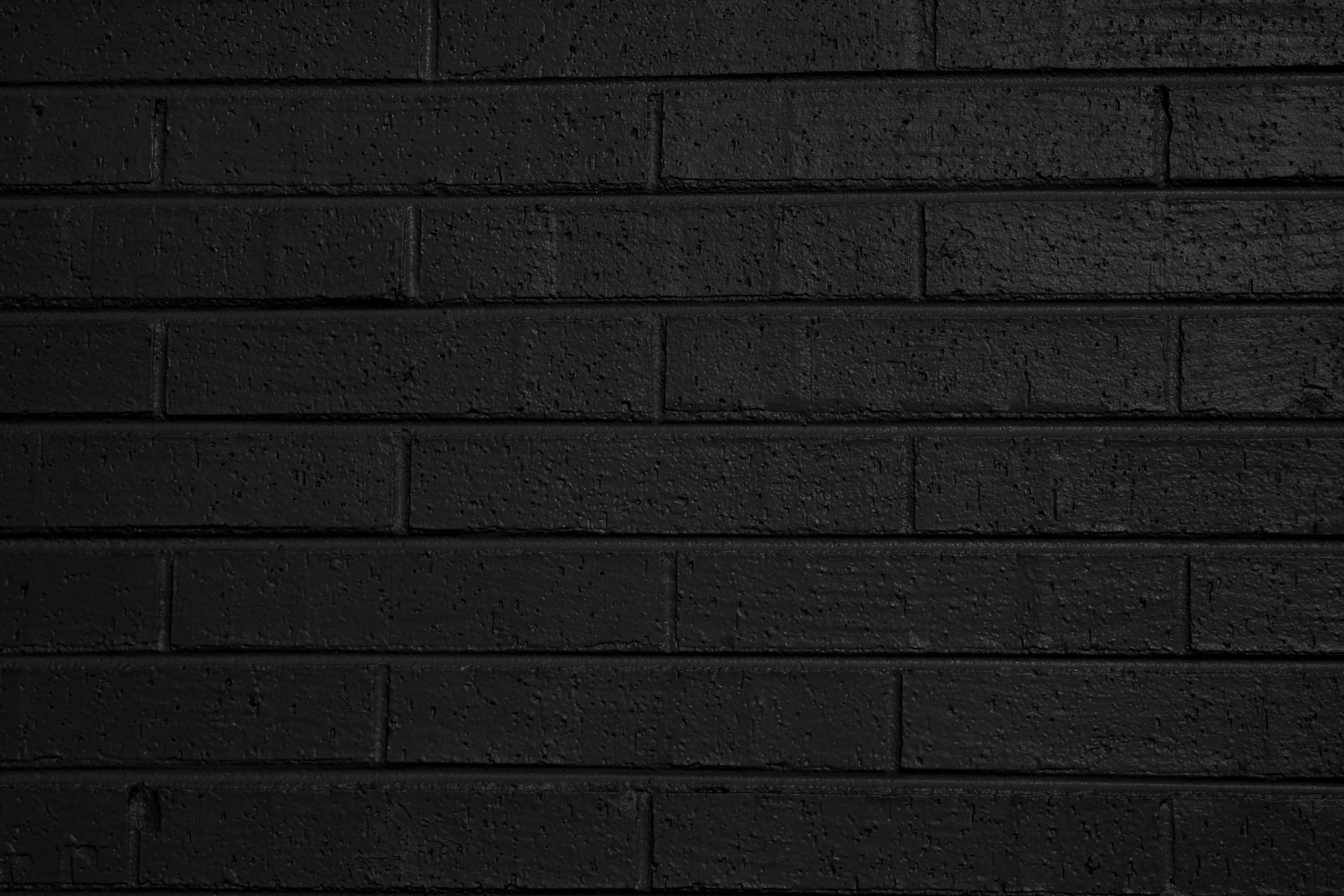 Dark Wall 桌布 壁紙 — 暗啞黑色磚牆的特寫，帶有細微紋理和模糊的砂漿線。