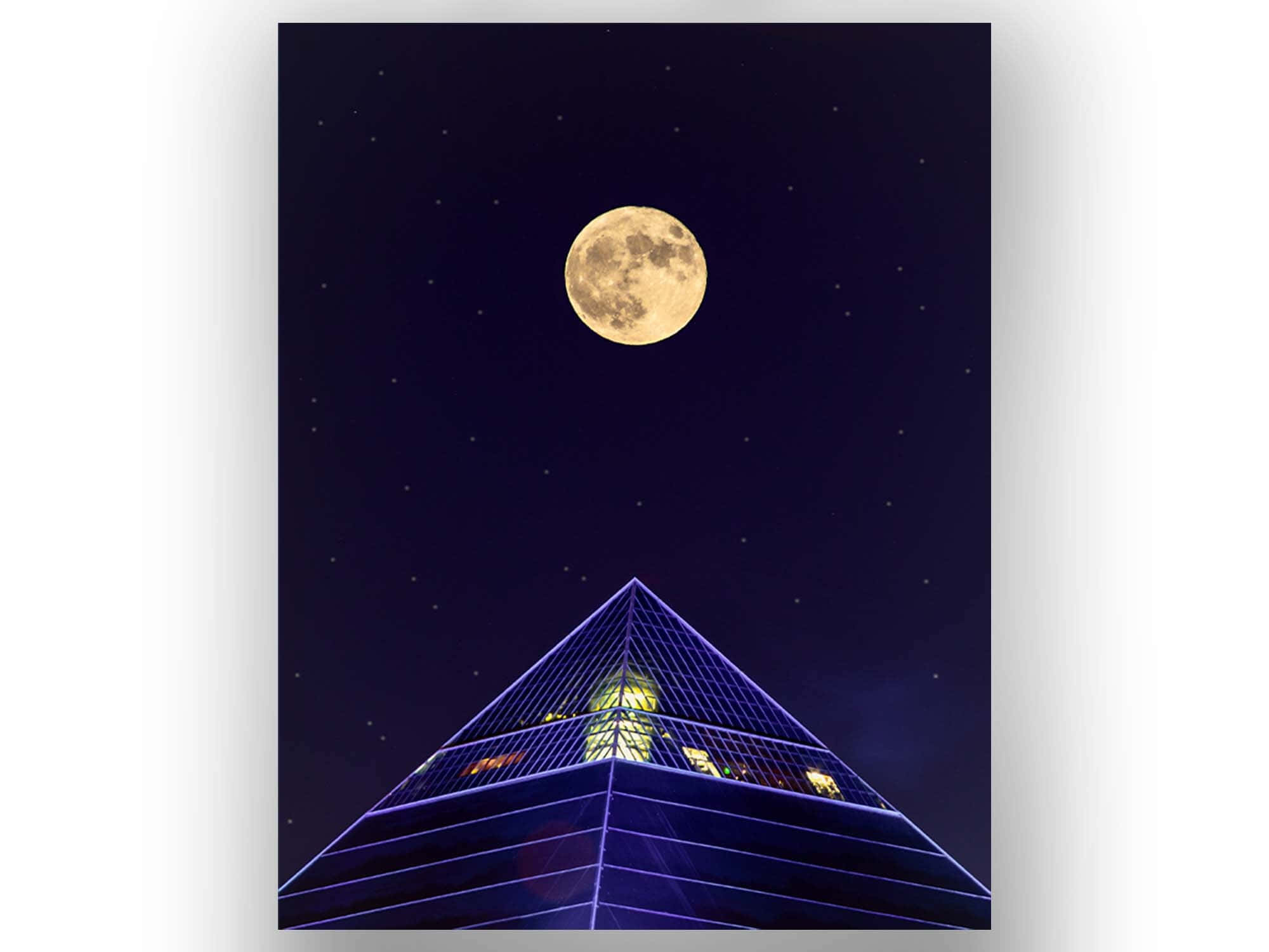 暗夜中的月亮金字塔 壁紙 — 滿月在繁星點點的夜空下，在發光的藍色金字塔形建築上方閃耀。