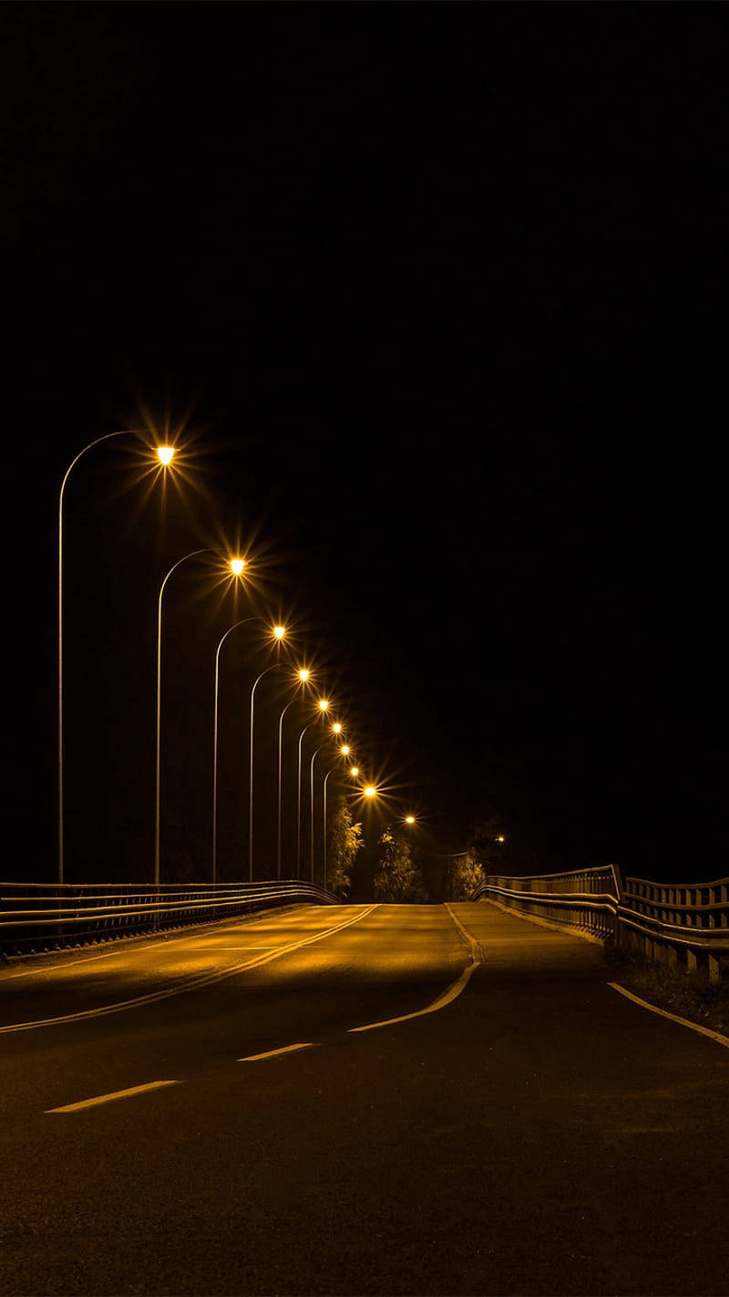 夜晚一條黑暗的道路被一排發光的街燈照亮。
