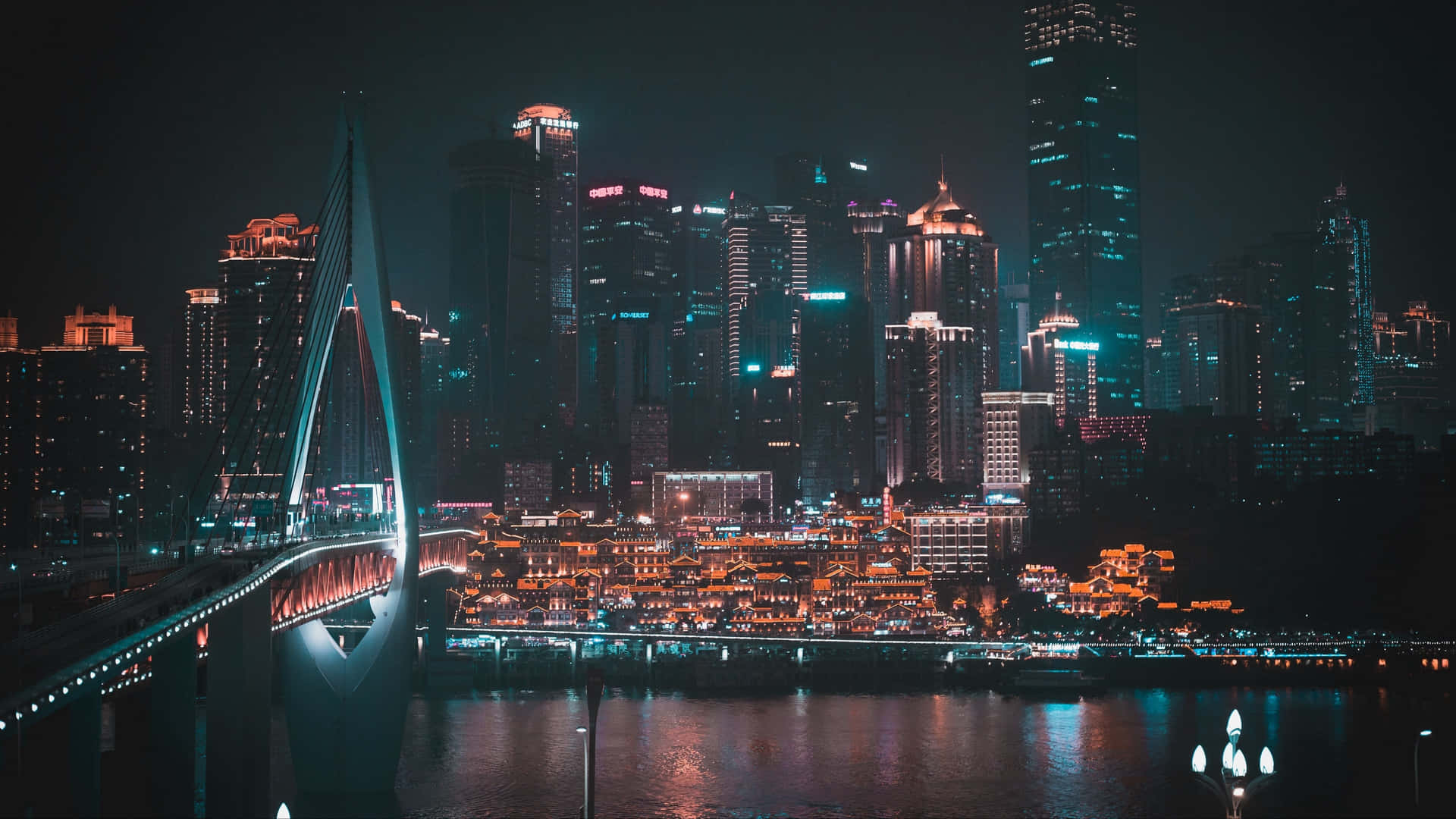 暗夜都市中繽紛奪目的燈光 4K 壁紙 — 現代城市景觀的迷人夜景，一座發光的橋樑橫跨河流，反射著摩天大樓和傳統建築的霓虹燈光。