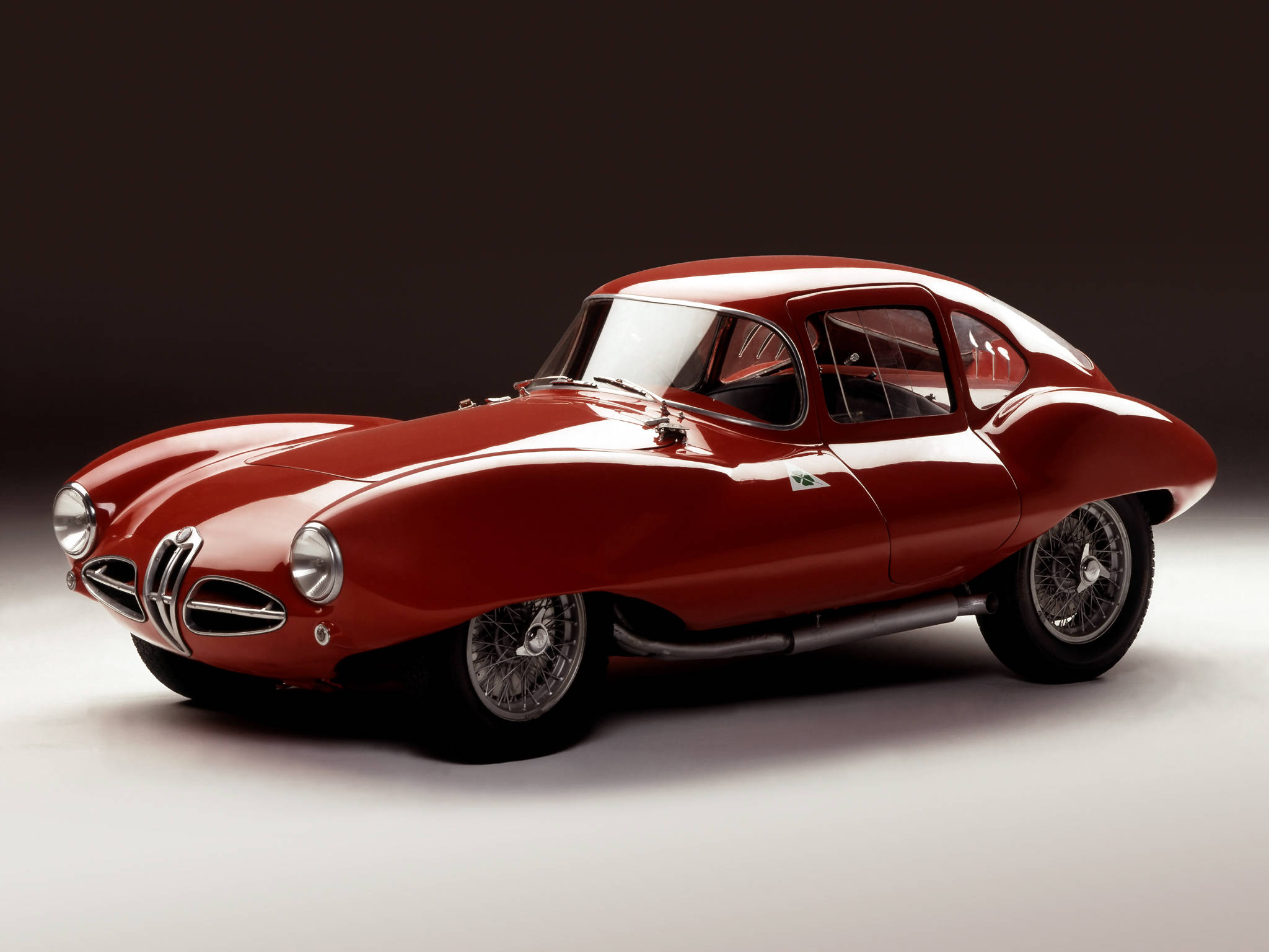 暗室中復古紅色Alfa Romeo iPhone壁紙 壁紙 — 一輛光澤的紅色經典阿爾法羅密歐跑車，配有鋼絲輪圈和鍍鉻裝飾，在深色工作室背景下擺拍。
