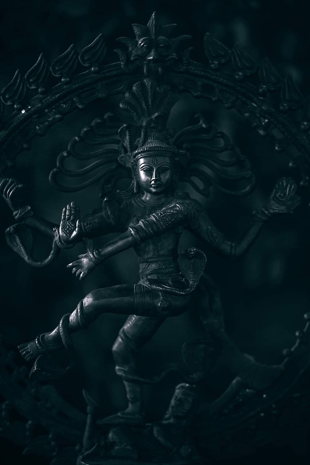 一尊深色的多臂神祇雕像，帶著耀眼的光環起舞。