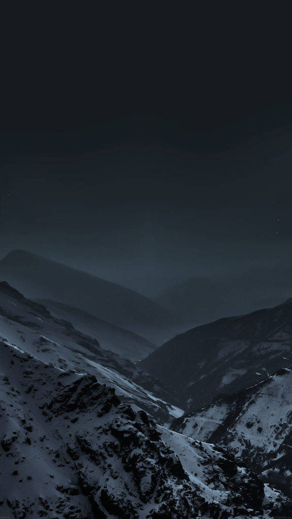 暗色山脈 iPhone 活動壁紙 壁紙 — 一片荒涼的積雪山谷，在黑暗的星空下，瀰漫著霧氣般的氛圍。