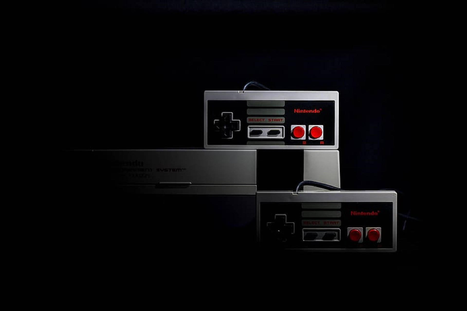 暗色背景下的NES遊戲套裝 壁紙 — 兩個經典 Nintendo Entertainment System 控制器和主機堆疊在黑色背景上，帶有戲劇性的燈光。