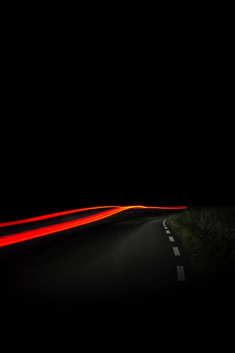 來自汽車的紅色光軌沿著夜晚黑暗蜿蜒的道路彎曲。