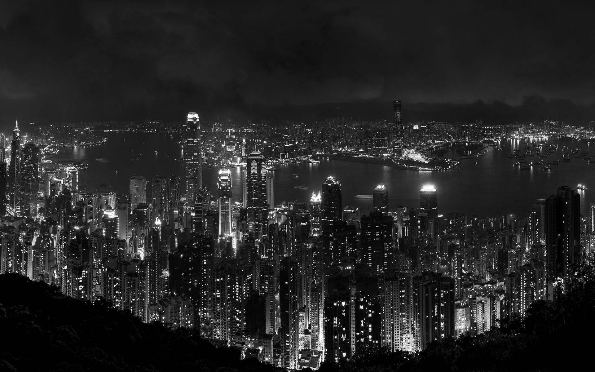 黑白夜景城市景觀，燈火通明的摩天大樓和港灣。