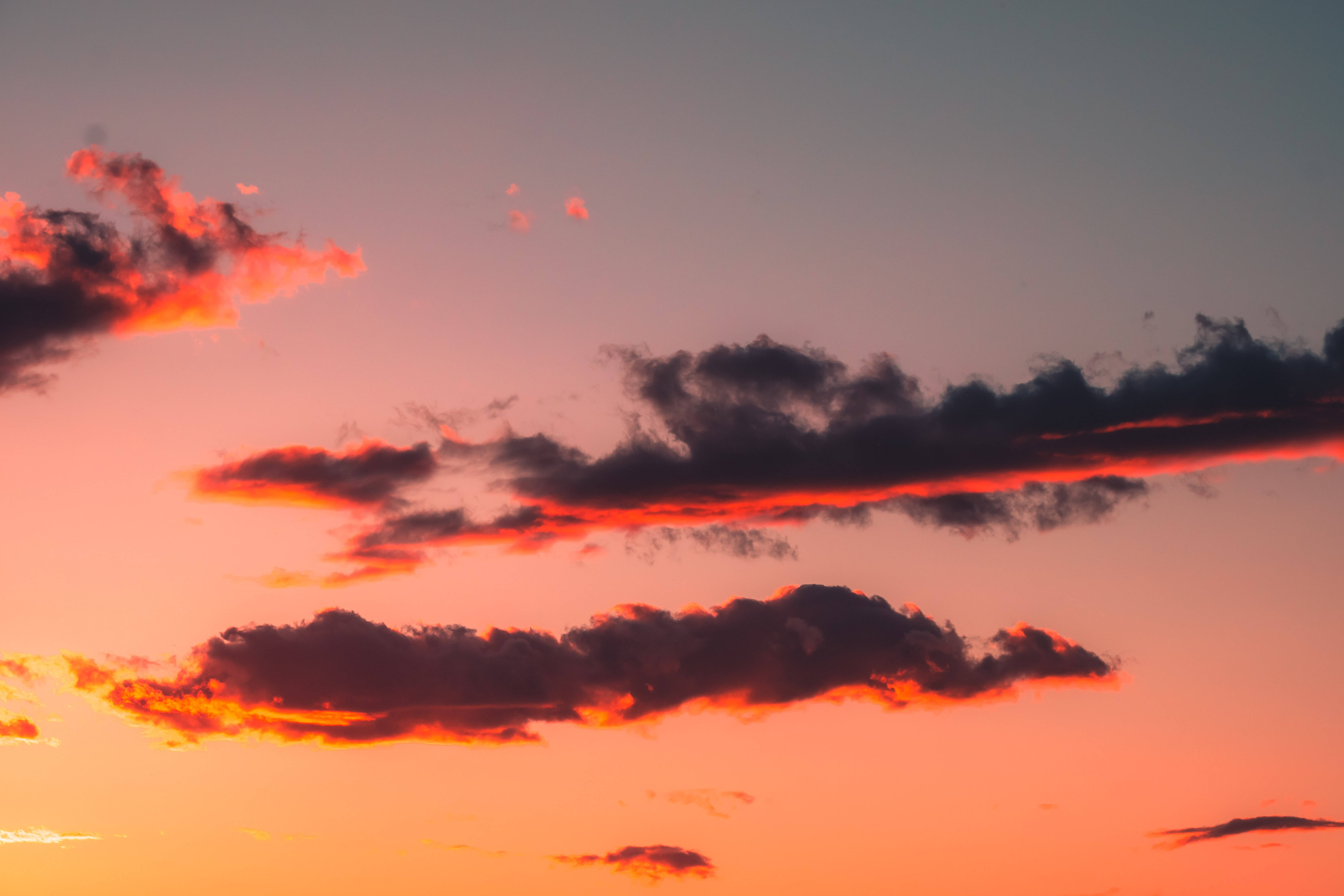 暗雲繚繞的美麗天空 壁紙 — 戲劇性的雲彩劃過充滿活力的橙色和粉紅色日落天空，帶有深紫色漸變。