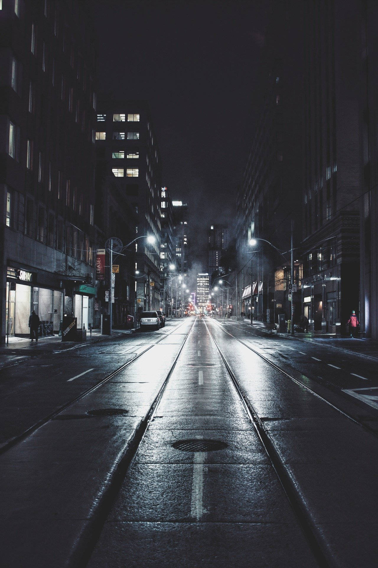 雨夜中濕滑的城市街道，閃爍的路燈和建築物窗戶。