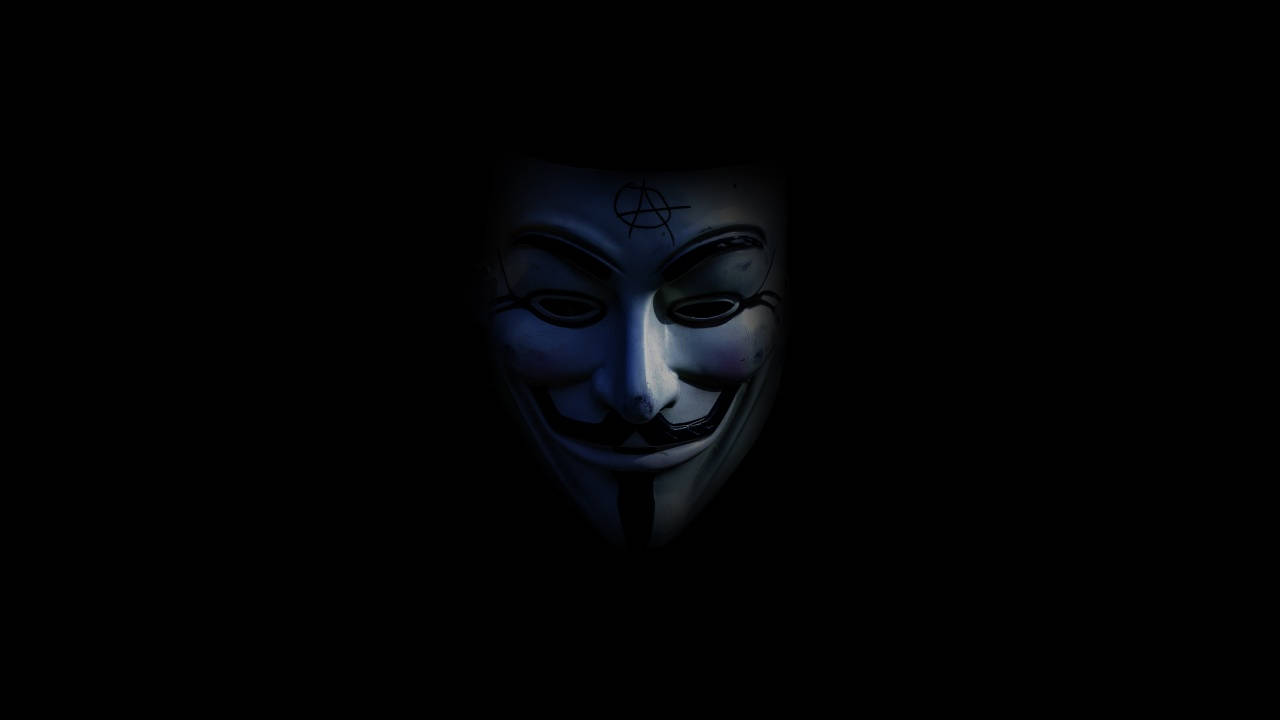 一個帶有無政府主義符號的白色 Guy Fawkes 面具在黑暗中發光。