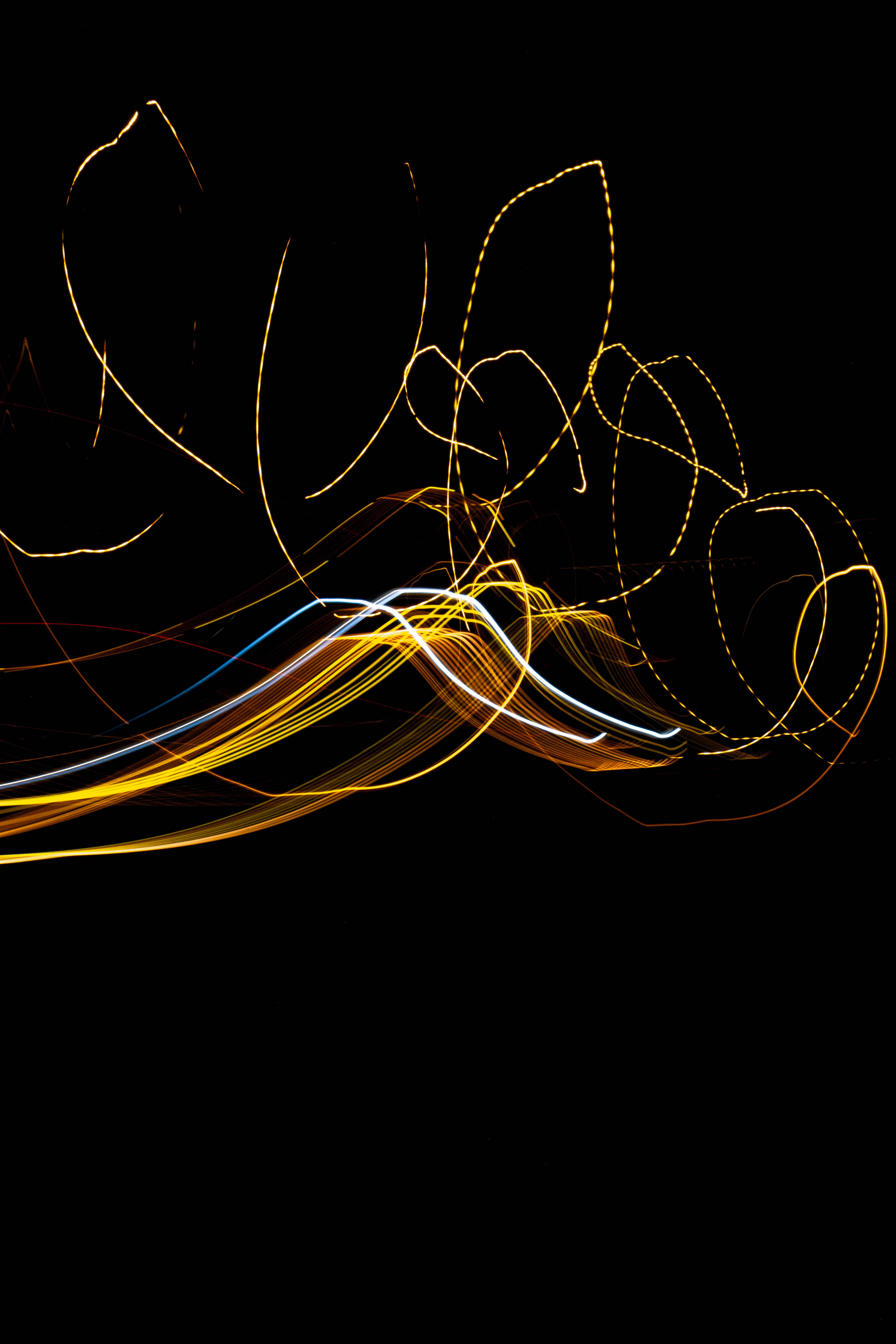 暗黑風格 iPhone 光線 streaks 壁紙 — 金色、白色和藍色的動態光軌在黑色背景上旋轉，營造出抽象運動效果。