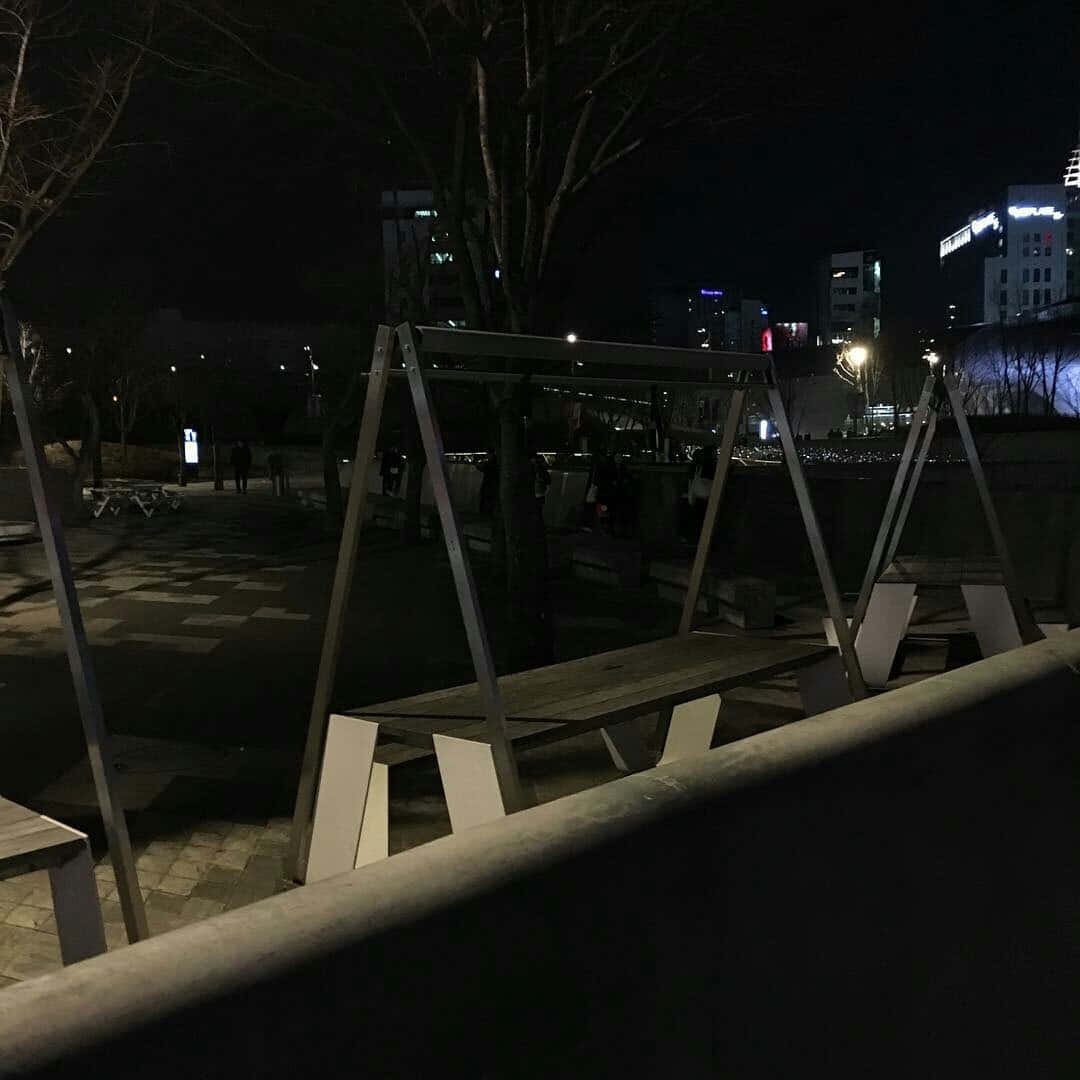 城市公園的夜景，空鞦韆和背景中燈火通明的建築物。
