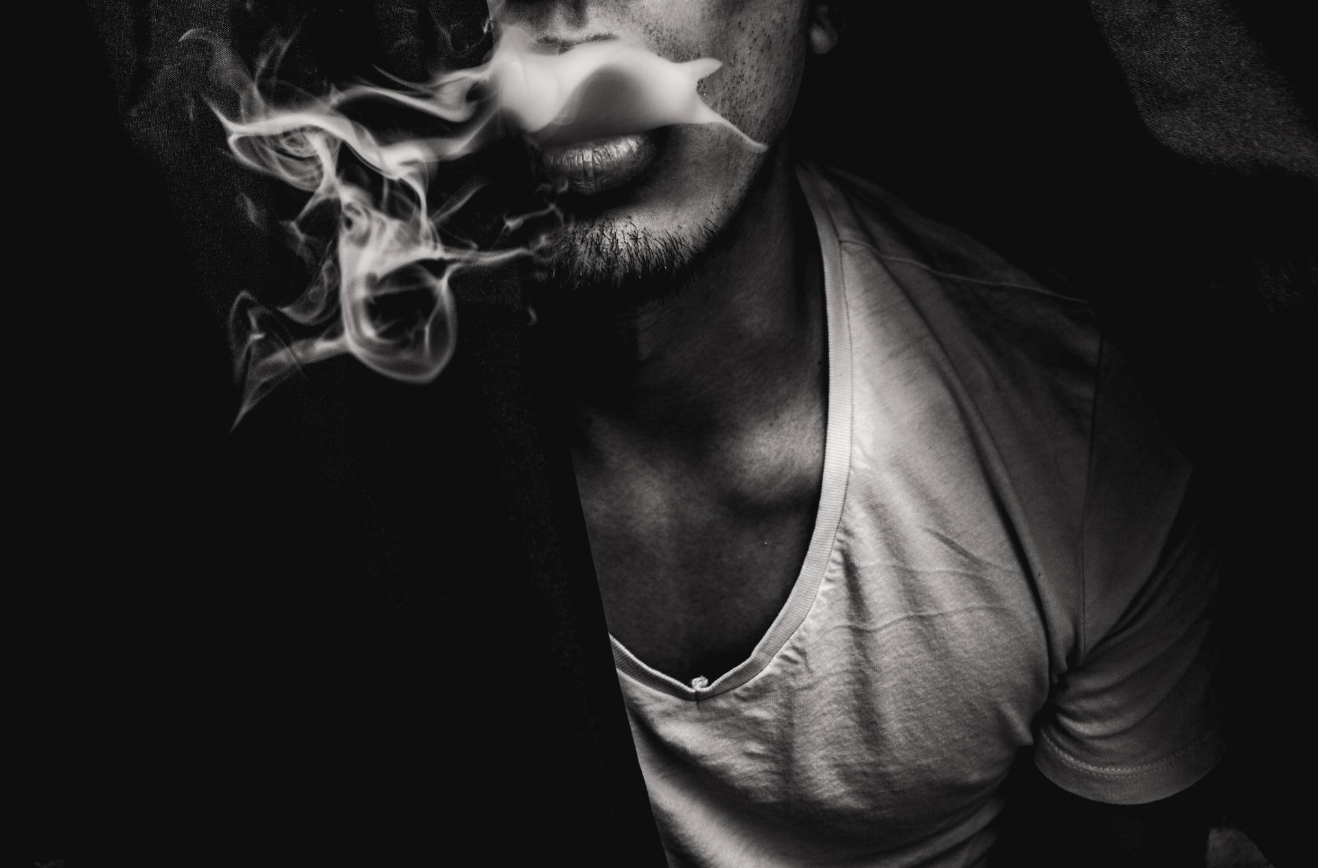 男人在黑暗的黑白肖像中呼出煙霧。