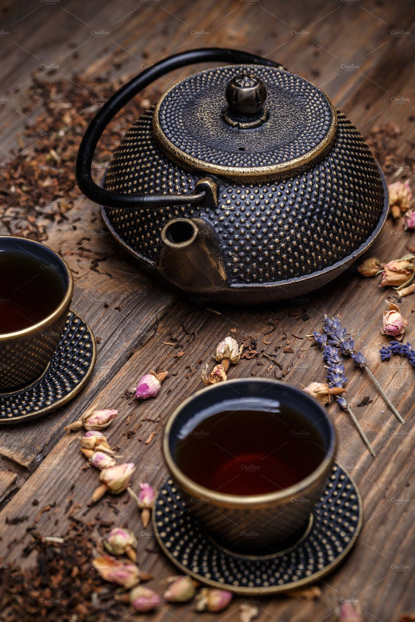 暫時休息，品一杯茶 壁紙 — 一個質樸的黑色紋理茶壺和兩杯深色茶放在一張散落著乾玫瑰花瓣和薰衣草的風化木桌上。