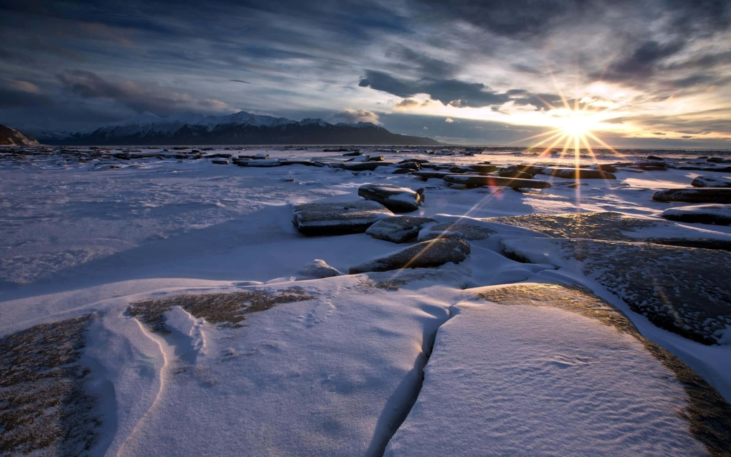 Winter Beach 桌布 壁紙 — 暮色中，陽光穿透雪白的浮冰和遠方積雪的山峰。
