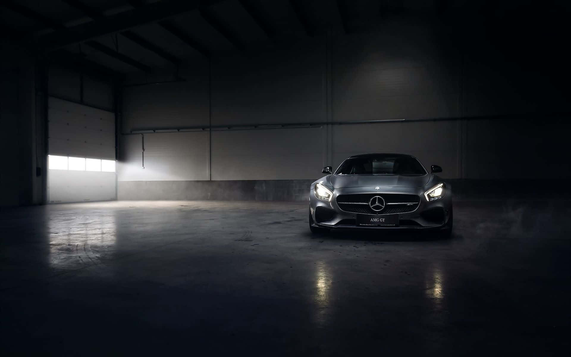 在黑暗的工業倉庫中照亮的流線型銀色 Mercedes-AMG GT 跑車。