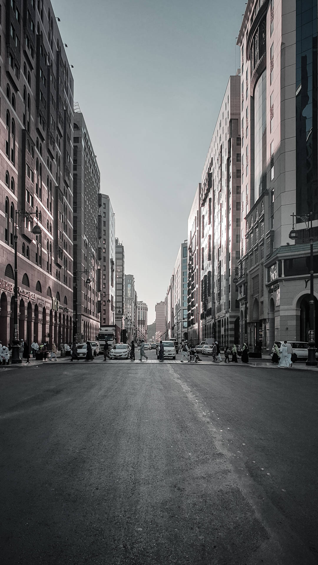 寬闊的城市街道，高樓大廈林立，人們在人行道上行走。