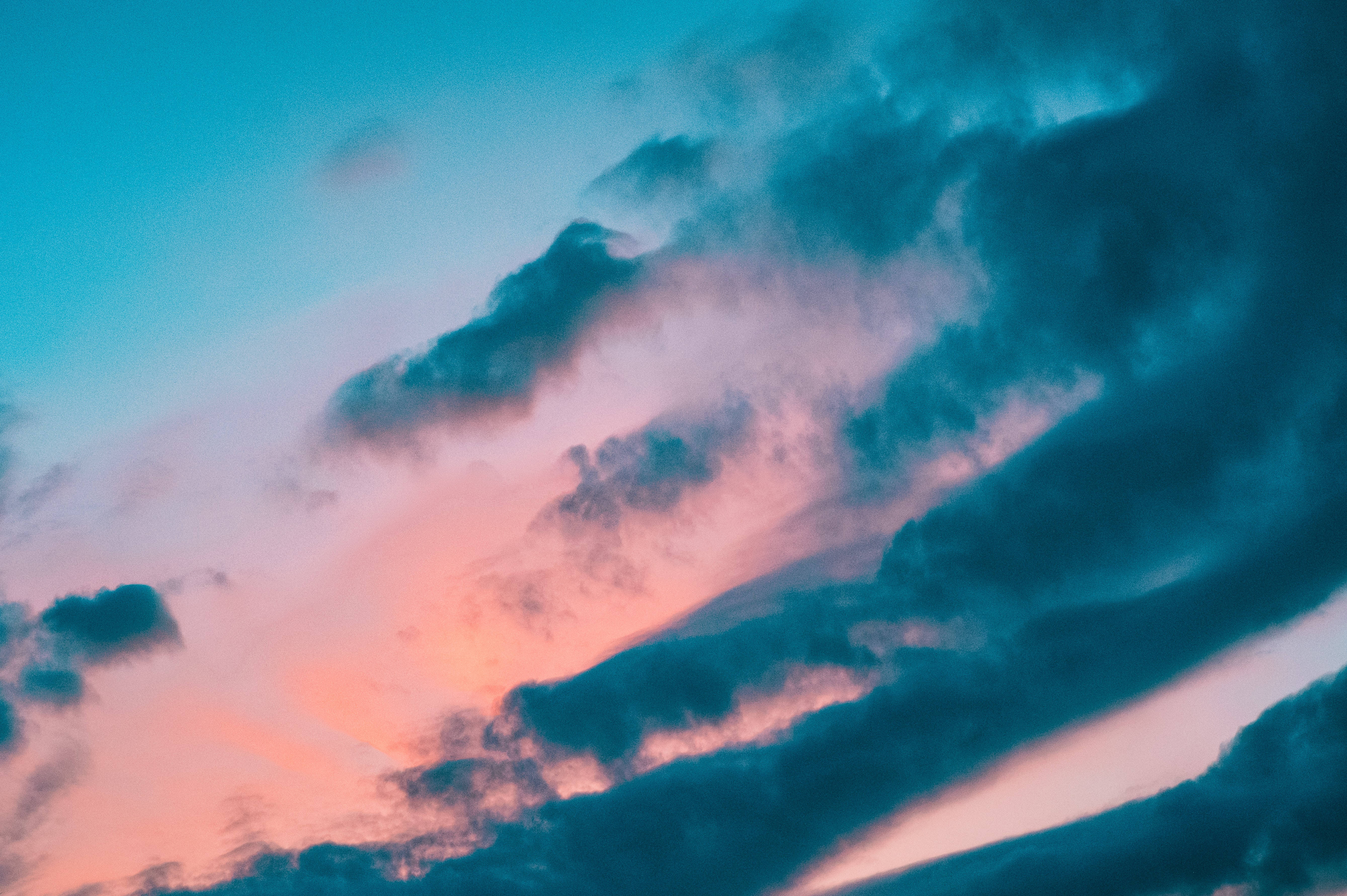 暮色美麗天空 壁紙 — 戲劇性的雲彩劃過黃昏的天空，天空被塗上鮮豔的粉紅色和深藍綠色調。