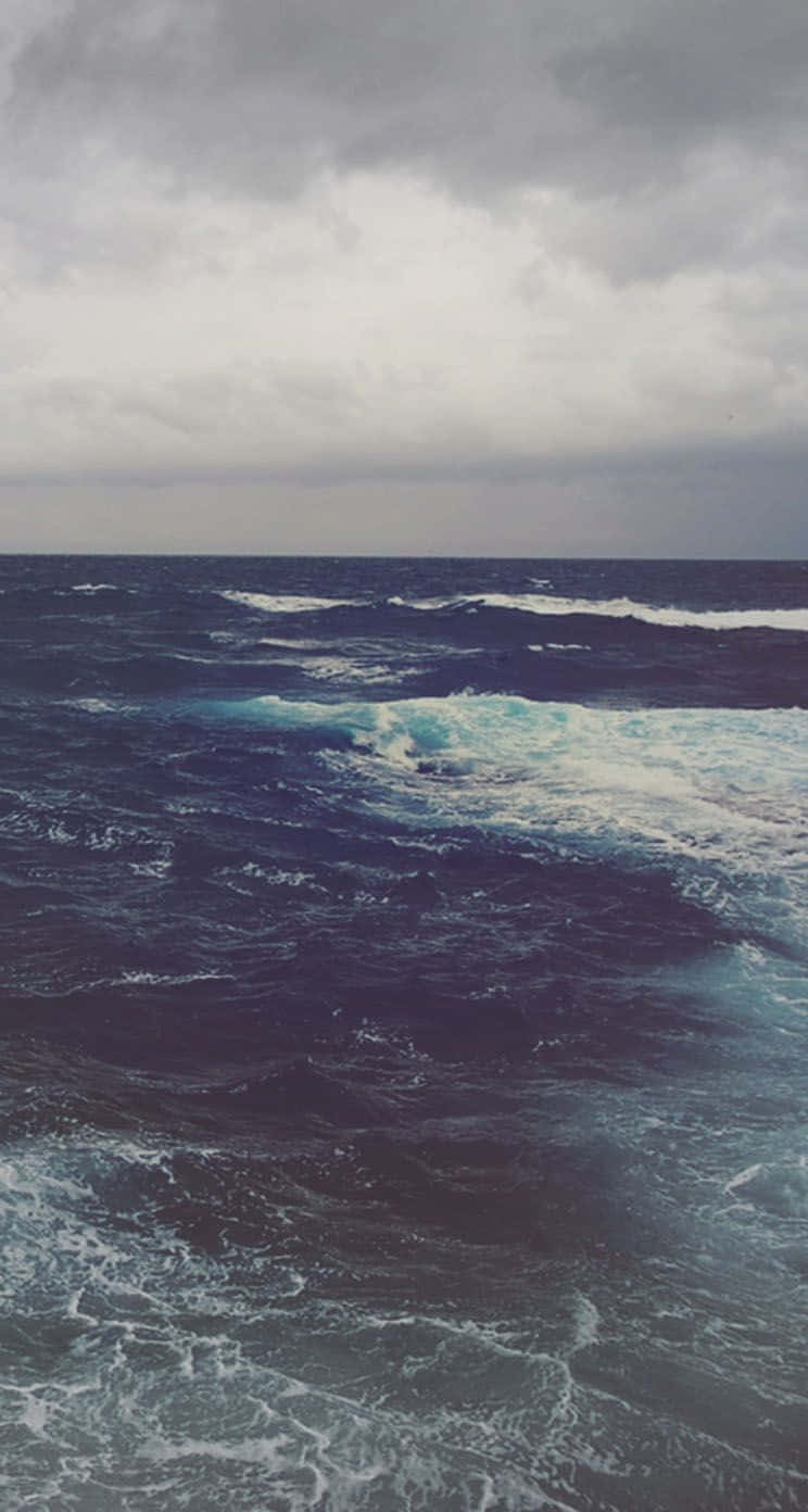 Dark Ocean 桌布 壁紙 — 暴風雨中的海洋，黑暗的波浪在沉重的灰色天空下翻騰。