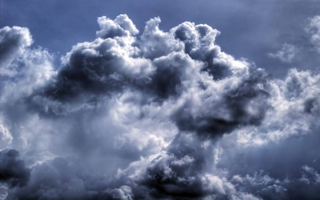 暴風雨般的深藍雲層 壁紙 — 戲劇性的風暴雲在深藍色和純白色中旋轉，映襯著陰沉天空。