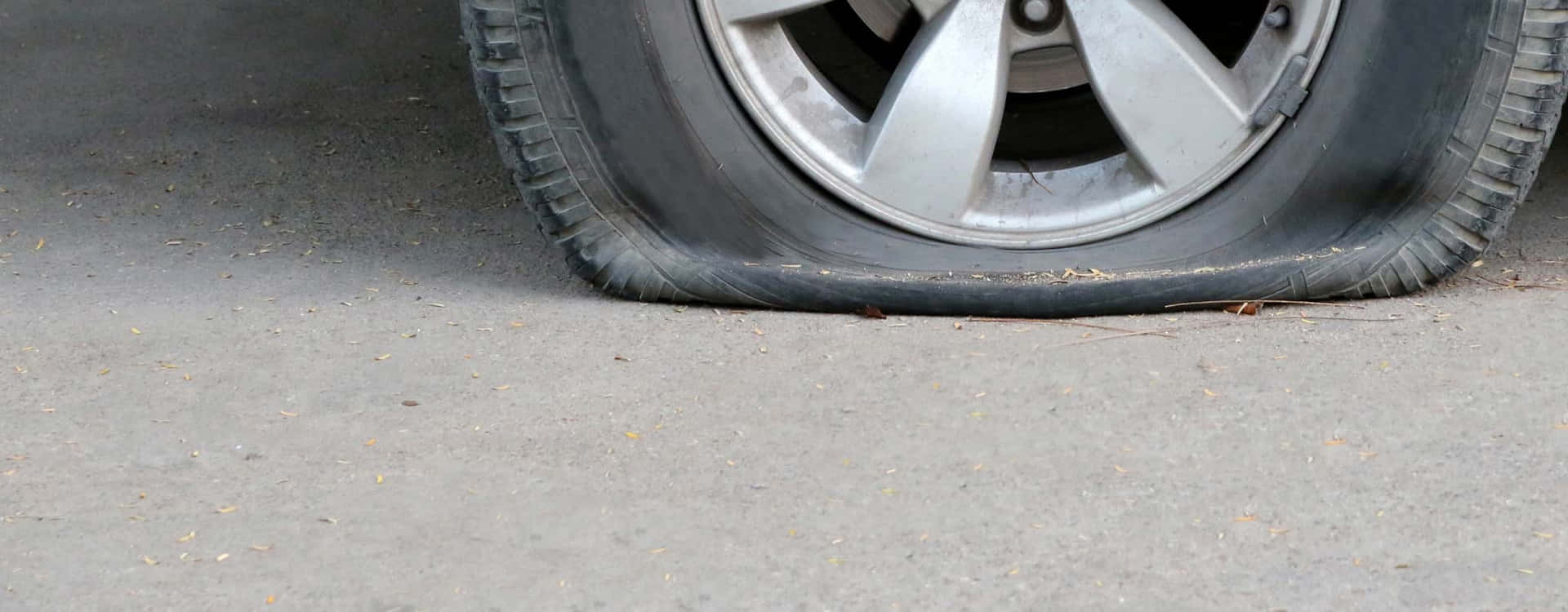 路面上扁平的汽車輪胎，輪圈有明顯損壞