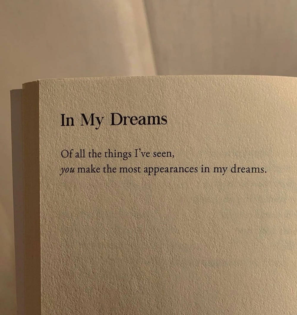 Beige Minimalist 桌布 壁紙 — 書頁特寫，上面有「In My Dreams」和「you make the most appearances in my dreams」的文字，在溫暖的燈光下。