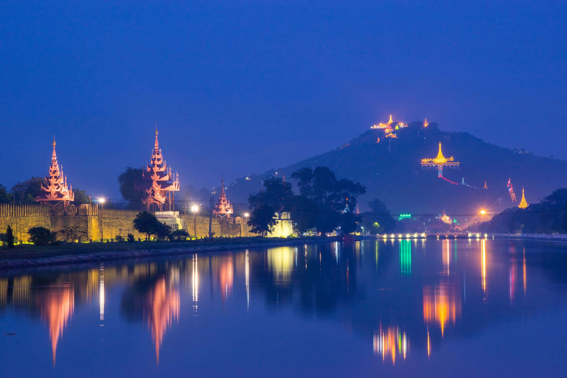 夜晚景色，發光的寶塔倒映在水中，背景是山脈。