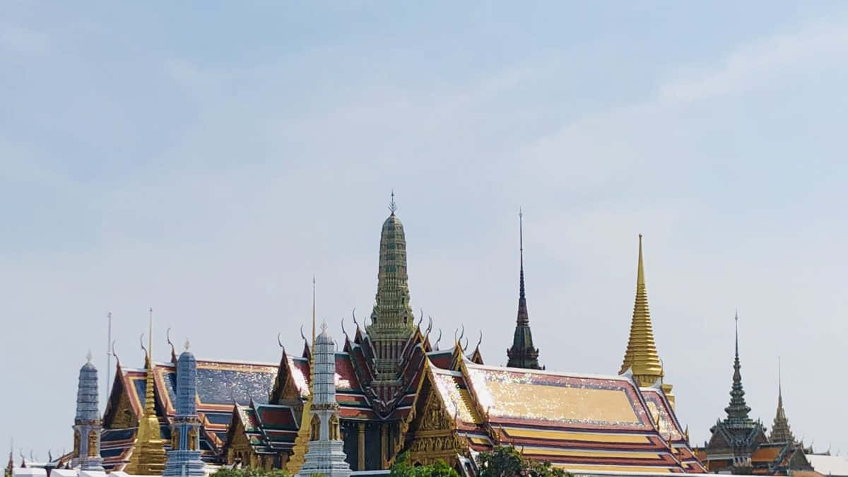 淡藍色天空下的金色寺廟尖塔和華麗屋頂。