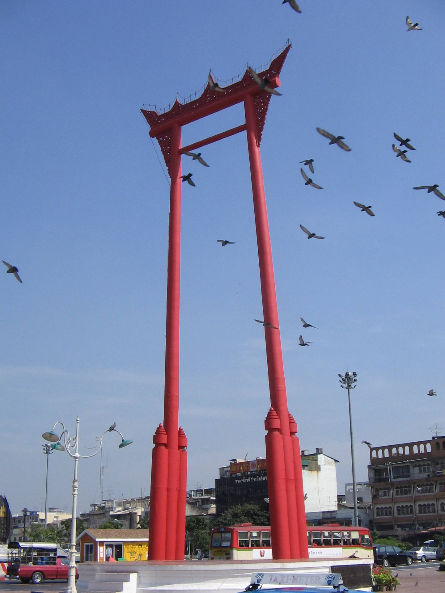 紅色巨型鞦韆紀念碑，鳥兒在城市環境中飛翔。