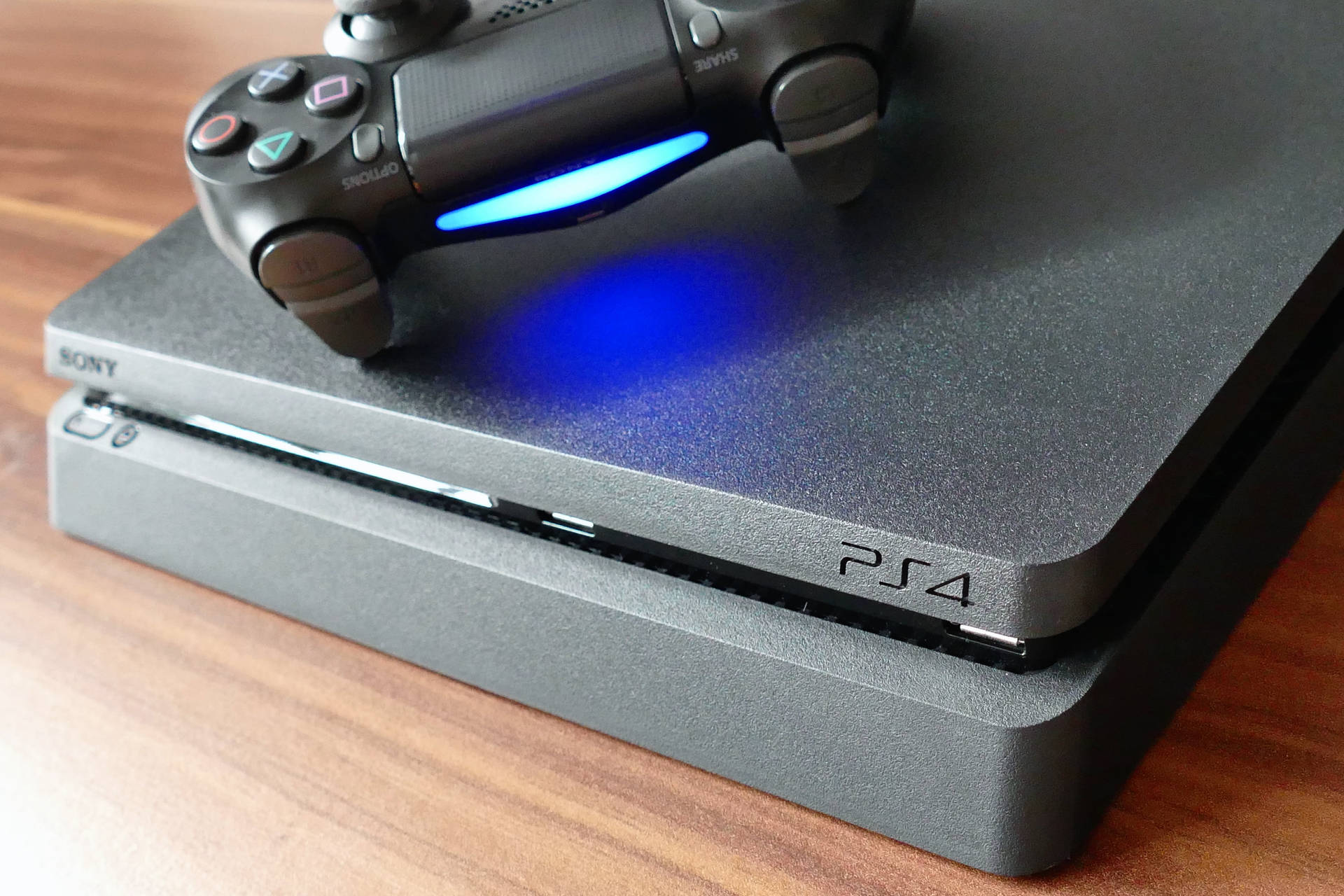 木桌上帶有藍光控制器的黑色PlayStation 4主機